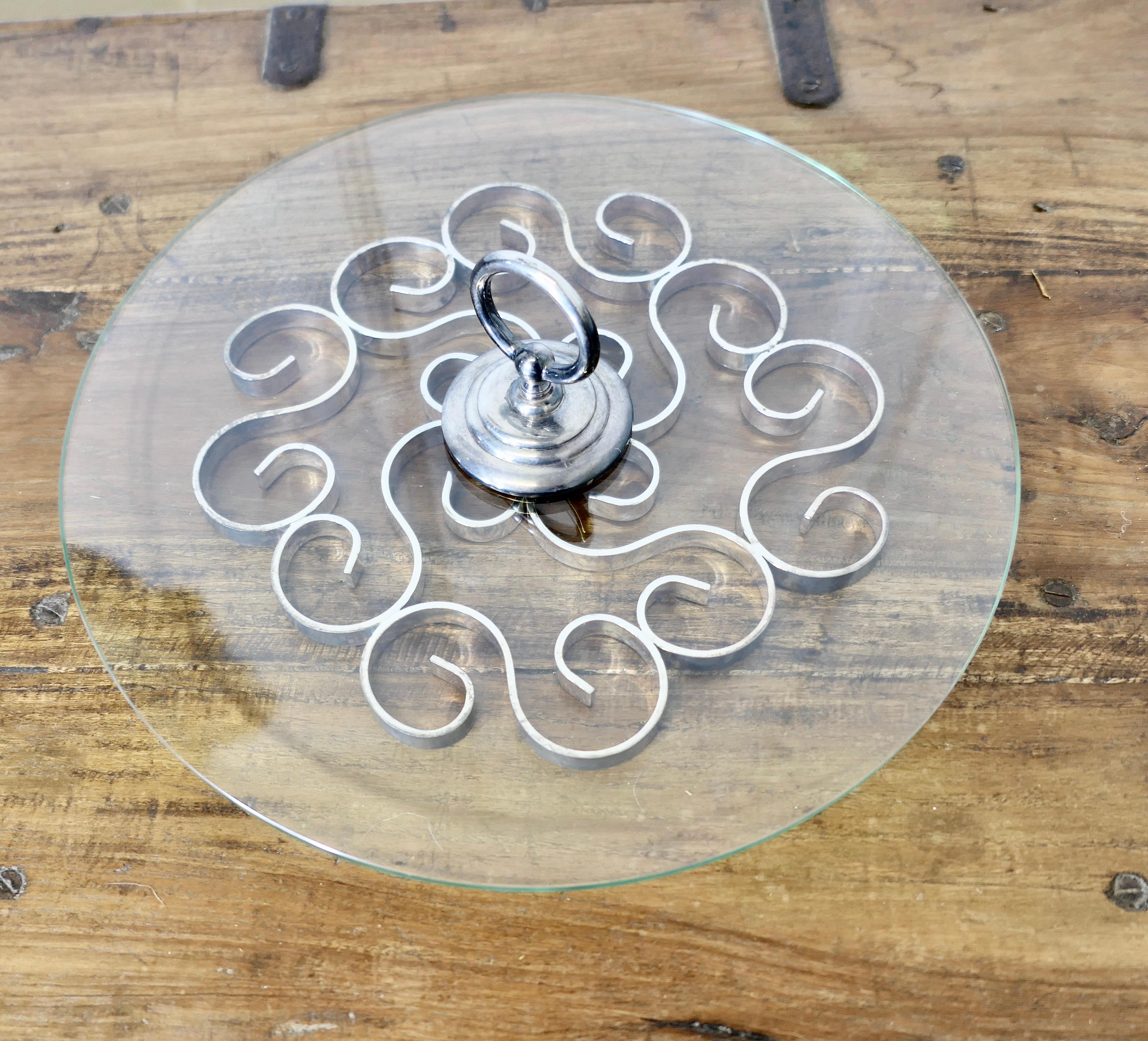 Piatto da formaggio dal design Art Deco, vetro e metallo argentato

Classico piatto per formaggi in vetro e metallo argentato con riccioli tortuosi su un disco di vetro spesso 
In buone condizioni d'uso.  
Il piatto è alto 4