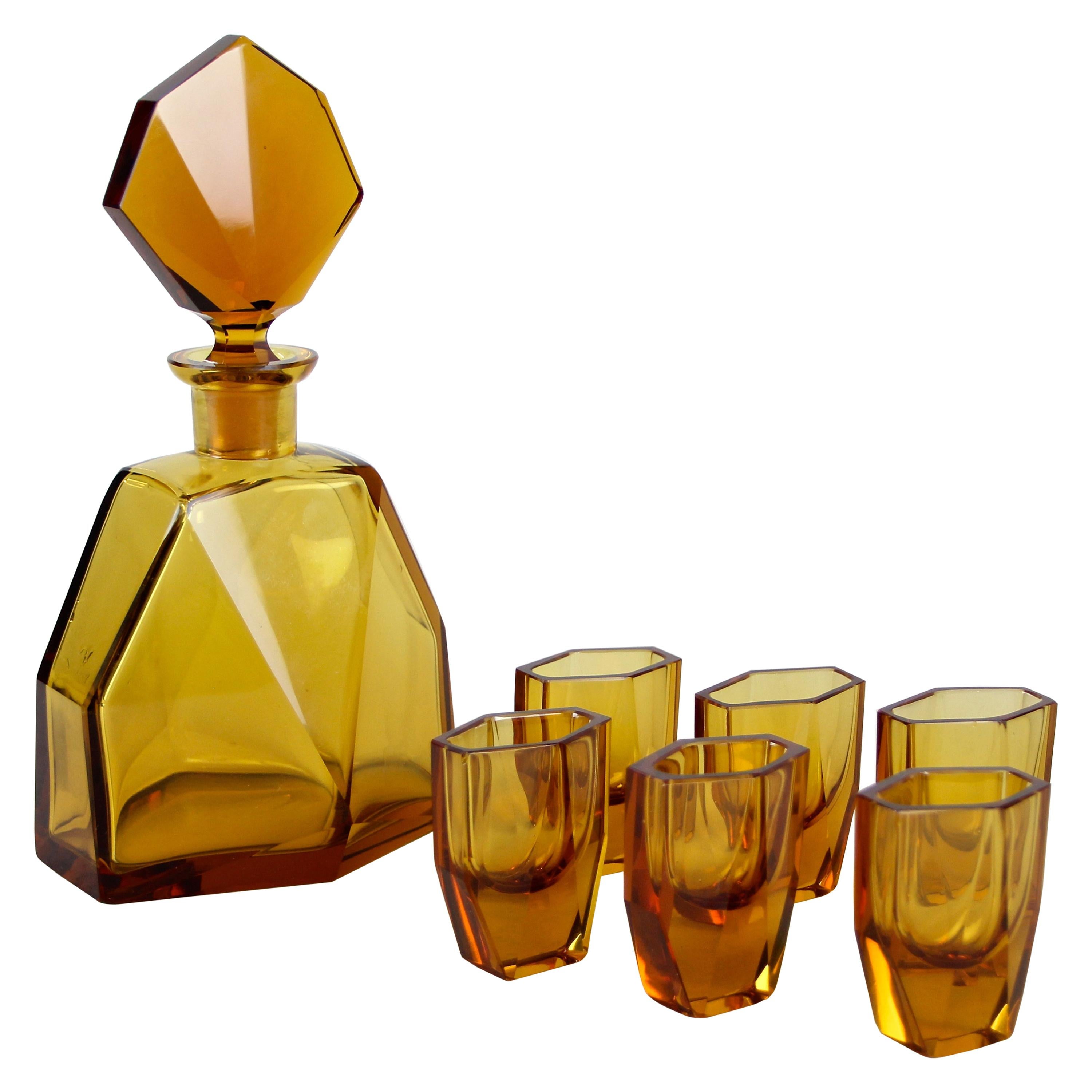 Outstanding design glass liquor set of seven from the Art Deco period in the Czech Republic, circa 1925. Reminding of the style of famous Ludwig Moser, this timeless designed amber colored liquor set consists of six unusual shaped shot glasses and a