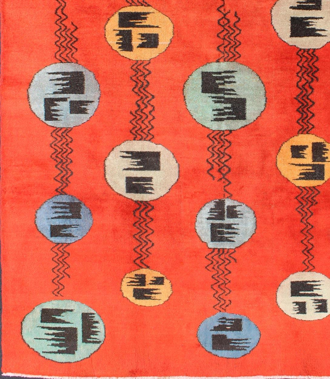 Art Deco Design Vintage Turkish Rug with Circular Motifs in Orange Red Colors.
Designed and commissioned by the Turkish megastar, Zeki Müren, this vintage contemporary rug highlights a retro palette and sporadically spaced circle motifs. Deriving