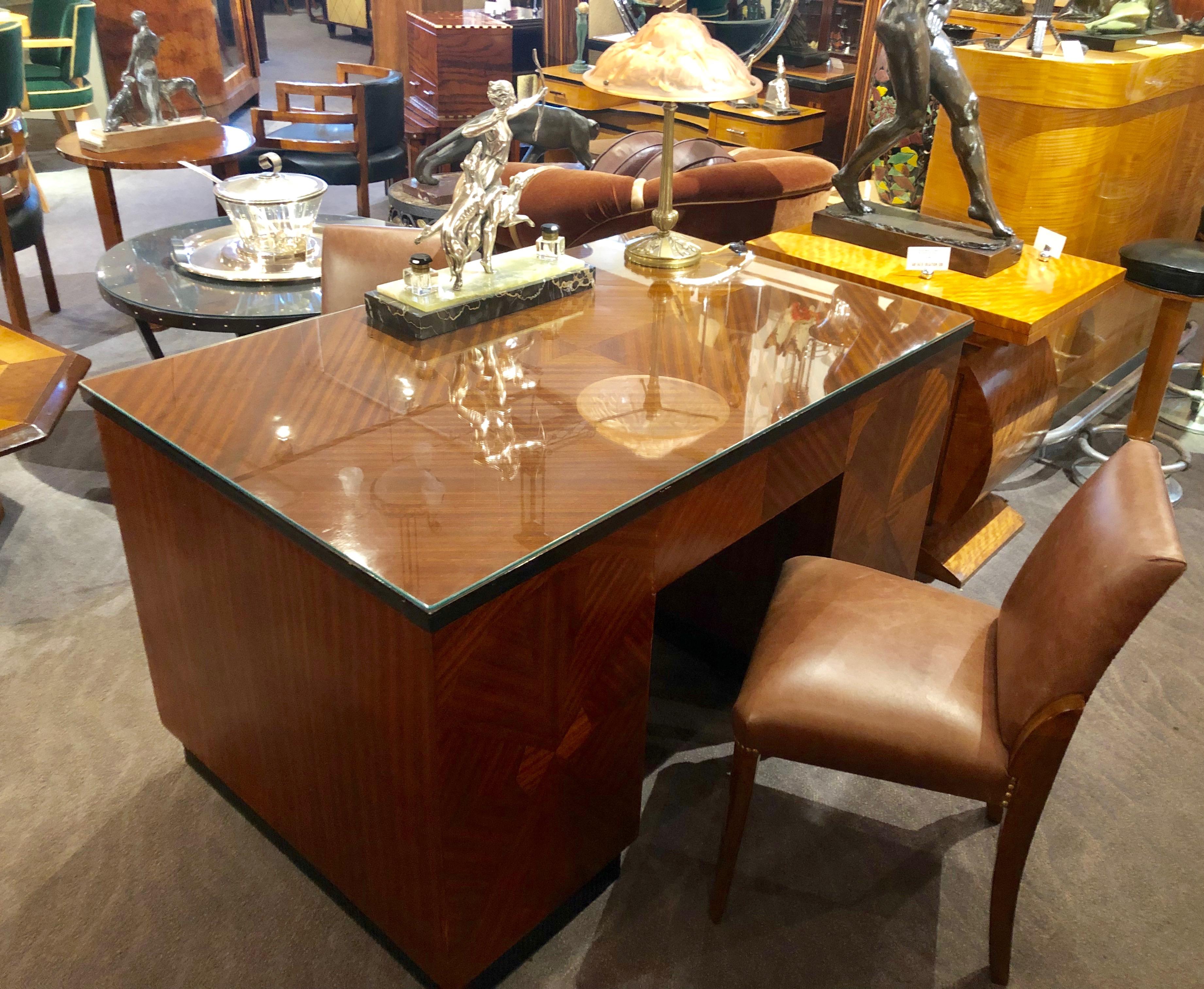 Bookmatched flamed mahogany Art Deco desk. Classic rectangular shape with two outside doors (one with shelves, one with files) and center drawer. All surfaces veneered with very unusual top showing angular cut straight grain to produce a stunning
