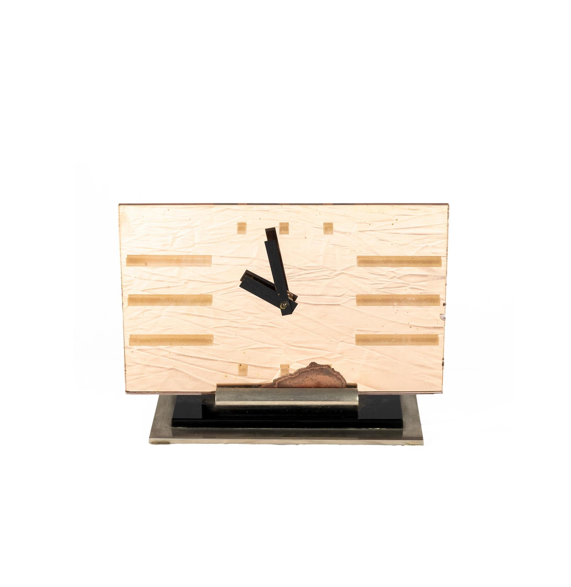Horloge de table Art déco en verre d'une teinte rose tendre, décorée d'index géométriques et d'aiguilles noires audacieuses.

Monté sur une base superposée en acier laqué noir, acier brossé et chrome.

L'horloge fonctionne sur piles, l'accès au