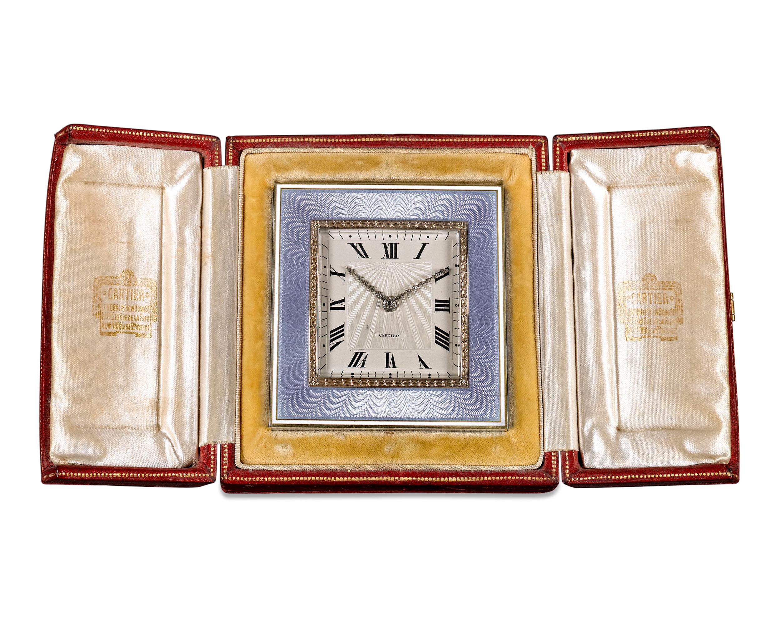 This elegant desk clock by Cartier features a soft blue guilloché enamel and gold frame. With Roman numerals marking the hours, the dial's radiant guilloché pattern is well-complemented by hands studded with fine white diamonds. An outstanding