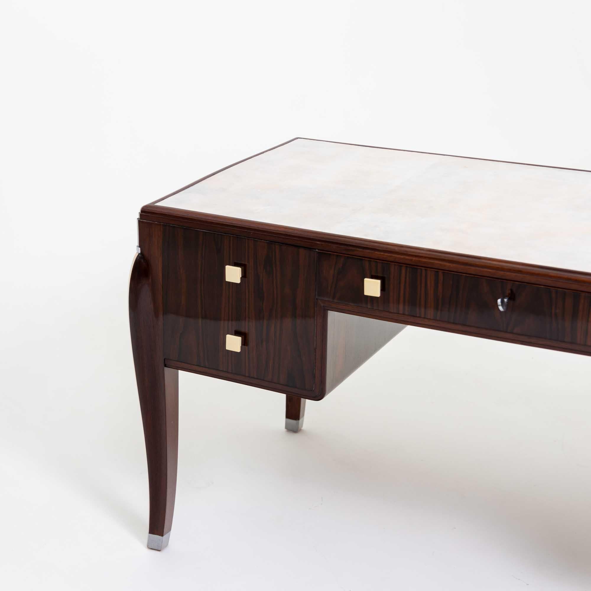 A fine Art Deco desk with a parchment writing surface. 
Details of nickel with cream colored pulls. Features three opening drawers ( center and two side drawers )
and two faux drawers on opposite side. Back of the desk has two drawers that open. 

