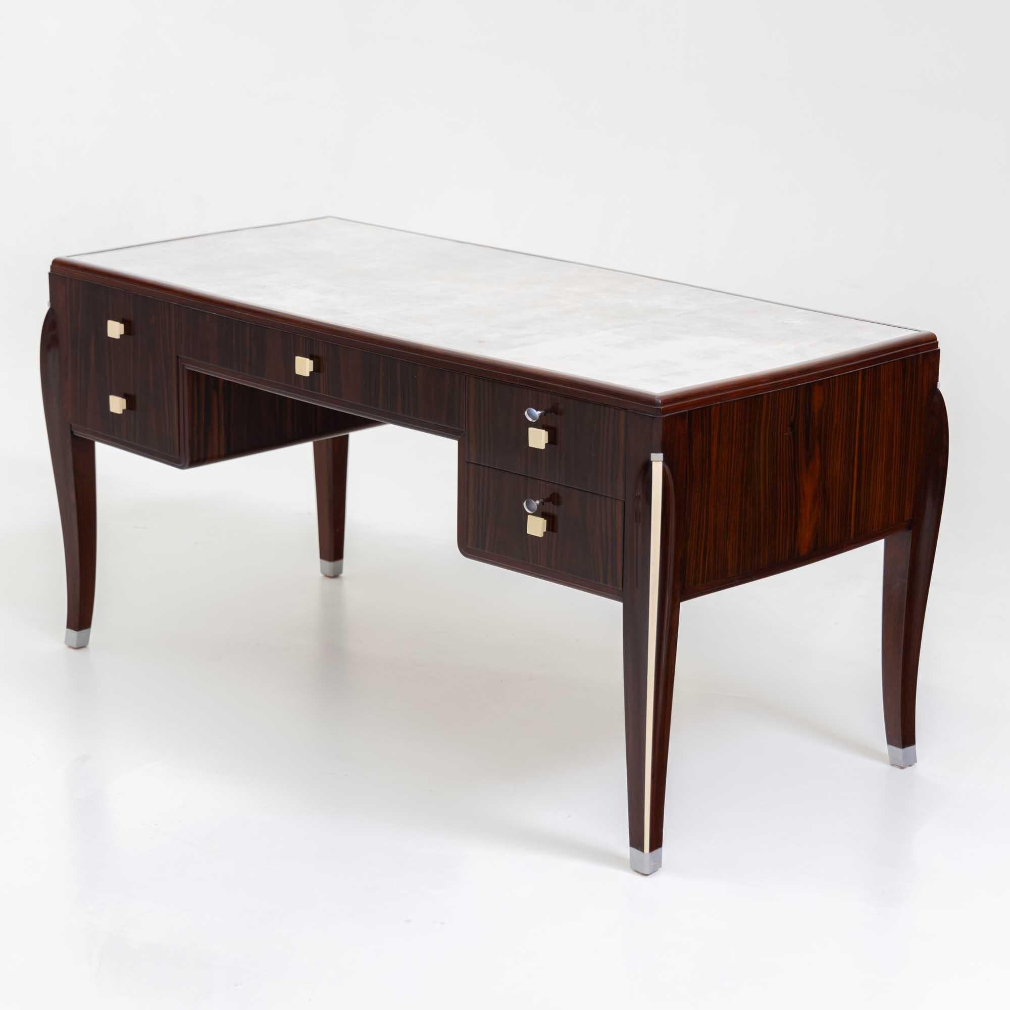 Elegant bureau Art Deco sur pieds fuselés et incurvés. Le bureau présente un design correspondant à l'avant et à l'arrière et offre un grand espace de rangement avec quatre tiroirs. Le tiroir de gauche est équipé de deux poignées blanc cassé pour