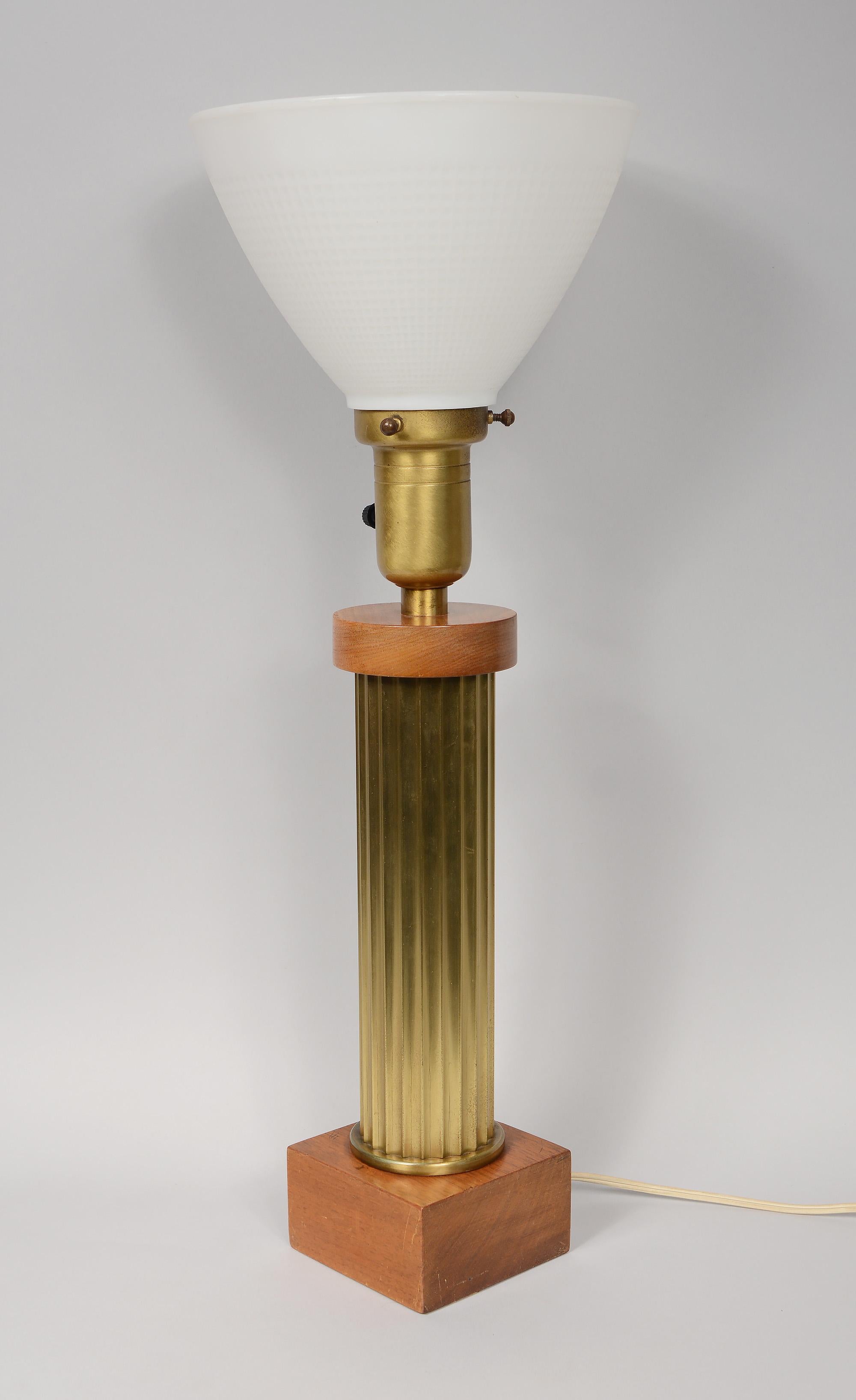 Small art deco table or desk lamp. This has a brass fluted column on a square wood base. The lamp has an eight inch diameter reflector that can be used as is or a shade can be put over it. The switch is a three way that takes a regular size edison