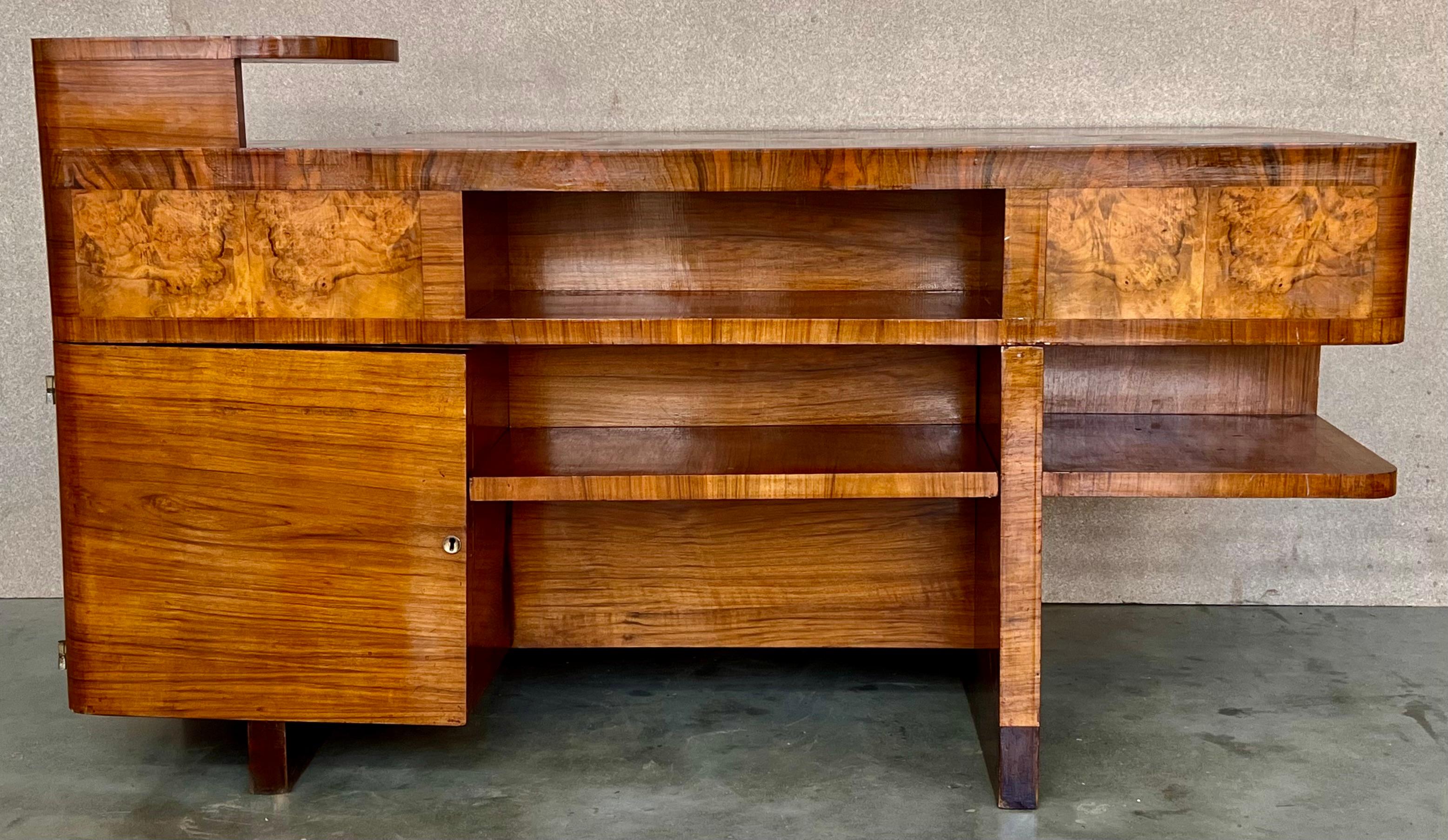 Art Deco Desk in Burl Walnut.
Beautiful Desk with two faces. In one side you can use like a desk, with five drawers and three compartments to organize your work,.
In the other side you have a big compartment closed by a door and three spaces .The