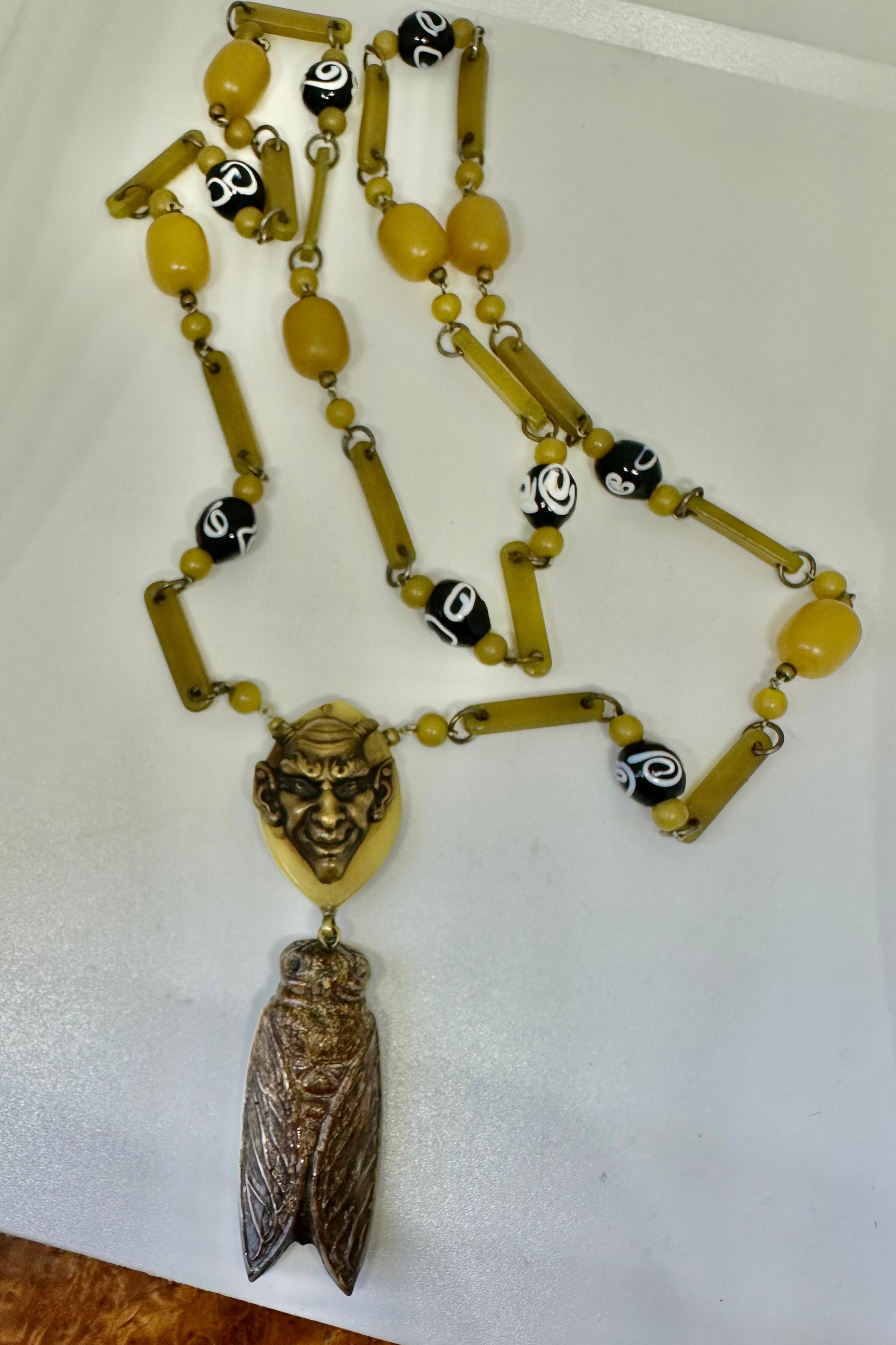 This is a stunning and very rare antique Art Nouveau - Art Deco French Devil and Cicada Insect Bug Pendant Necklace in Bakelite or the French form Galalith with Venetian Glass beads.  The extraordinary jewel with the devil motif is extremely rare!