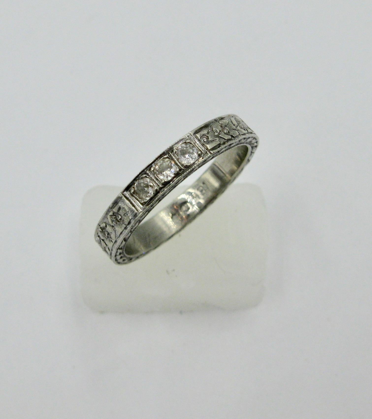 This is a stunning Antique Art Deco Diamond 18 Karat White Gold Wedding Engagement Band Ring.  The gorgeous ring has three gorgeous Old Mine Cut Diamonds set in a highly detailed engraved band with flower motifs and patterns.   A very gorgeous band