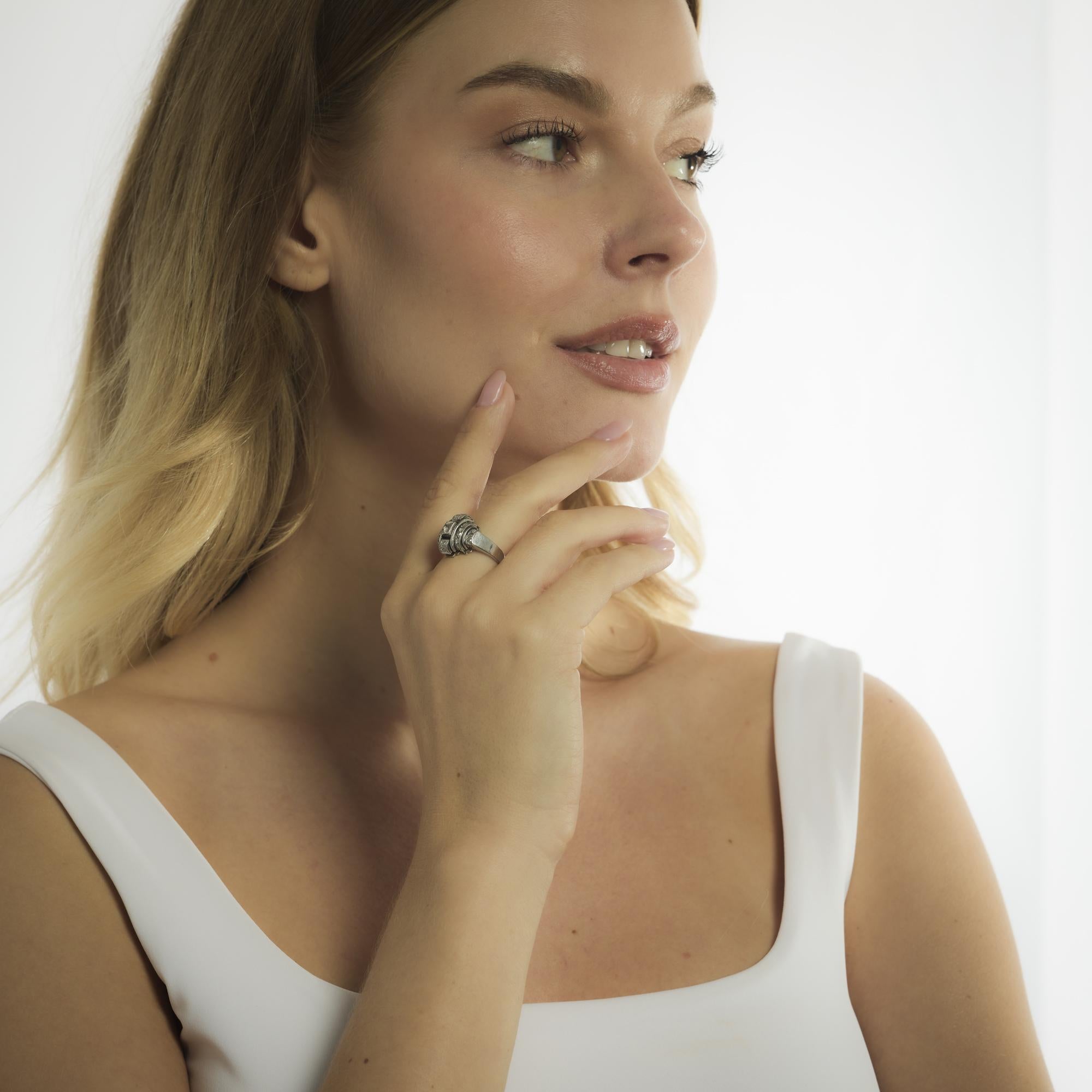 Dieser Art-Deco-Ring aus 18 Karat Weißgold aus den 1930er Jahren enthält einen Diamanten im alten europäischen Schliff von etwa 0,20 Karat in der Farbe H und der Reinheit SI. Um ihn herum formen sechsundzwanzig Diamanten im Rosenschliff mit einem