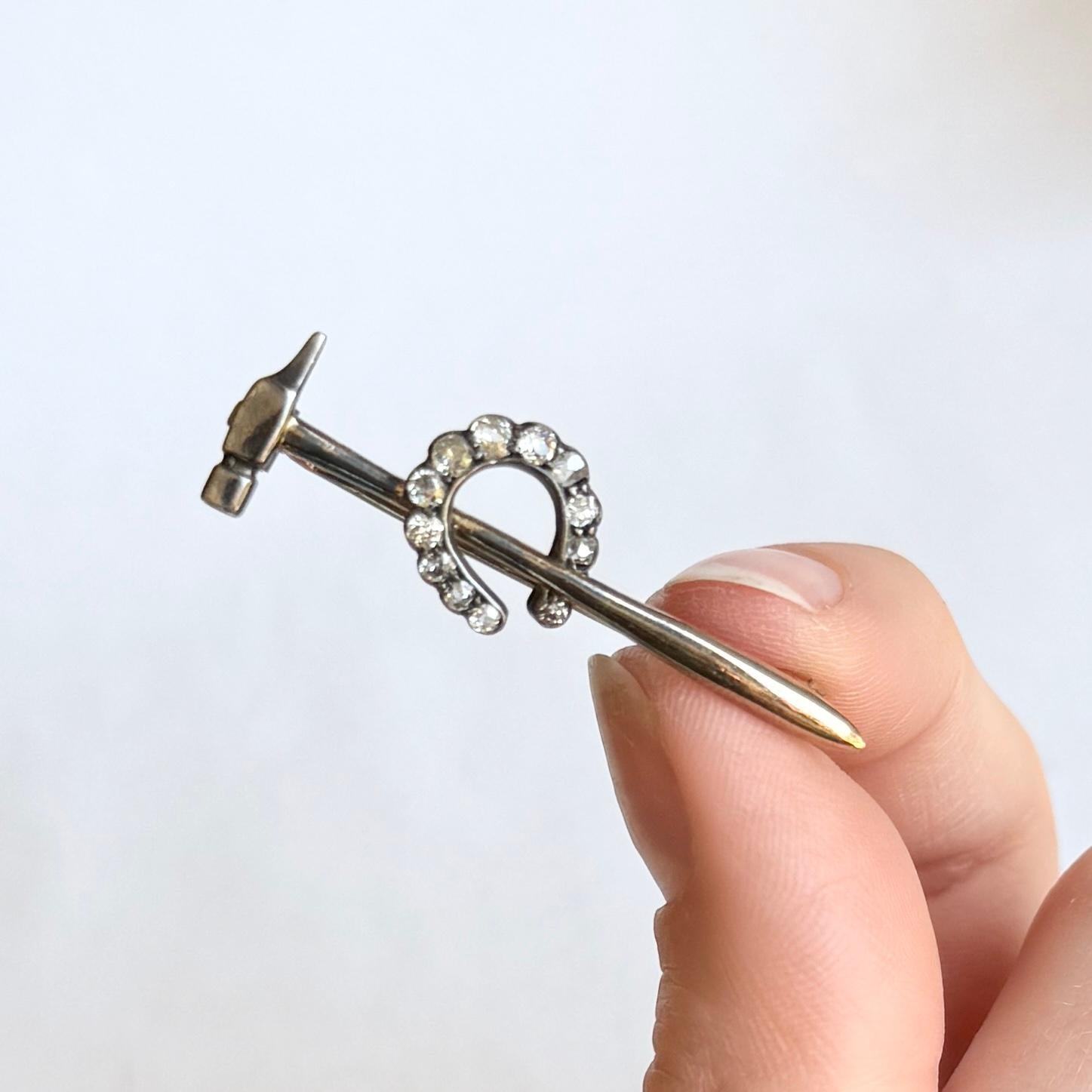 Cette magnifique broche présente un fer à cheval incrusté de diamants de taille ancienne et repose sur un marteau. Le total des diamants est de 42 points.

Longueur de la broche : 38 mm

Poids : 2.5 g