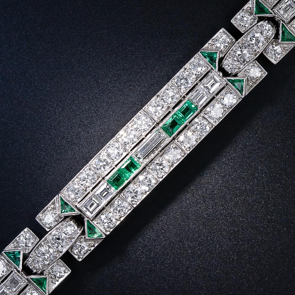 This original and quintessentially Art Deco diamond and emerald bracelet, circa 1925, radiates with bright-white and beautiful European-cut diamonds arrayed in two rows and bisected by horizontally-set baguette and square-cut diamonds which
