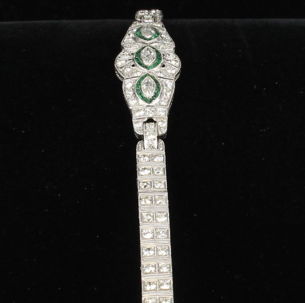 This platinum Art Deco bracelet is a bracelet of impressive stature.  Created in the 1920's, it displays 6.50 carats total weight of diamonds including the three marquis diamonds set in the center surrounded by elegant emeralds.  The bracelet is
