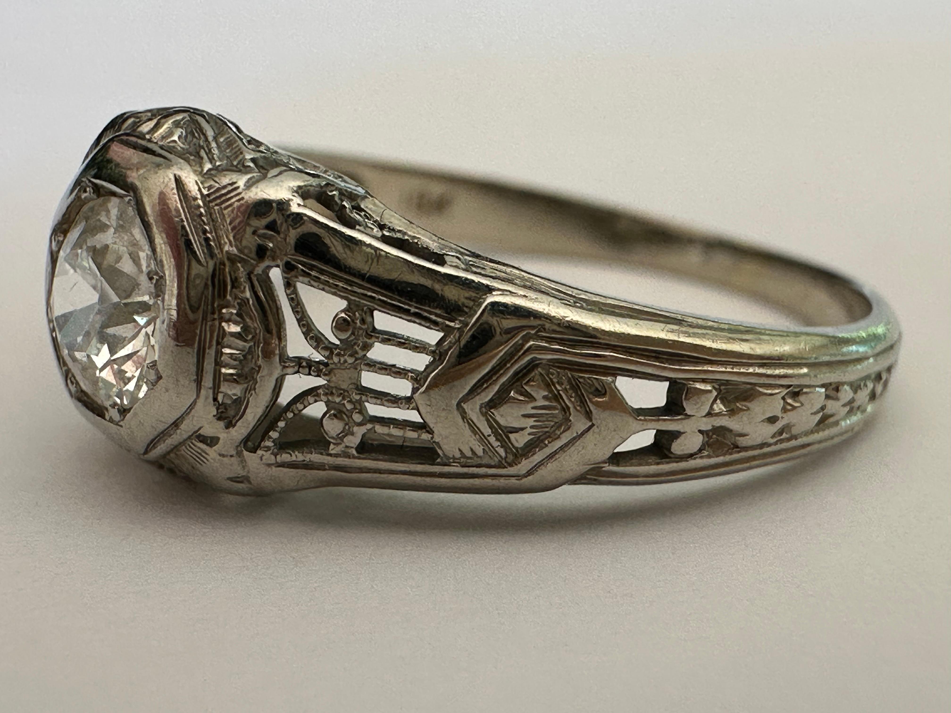 Un diamant de taille européenne ancienne totalisant environ 0,45 carats, de couleur G et de pureté SI1, est au centre de cette bague solitaire Art déco antique agrémentée de délicats piercings et d'un fin filigrane. Serti en or blanc 18 carats. 