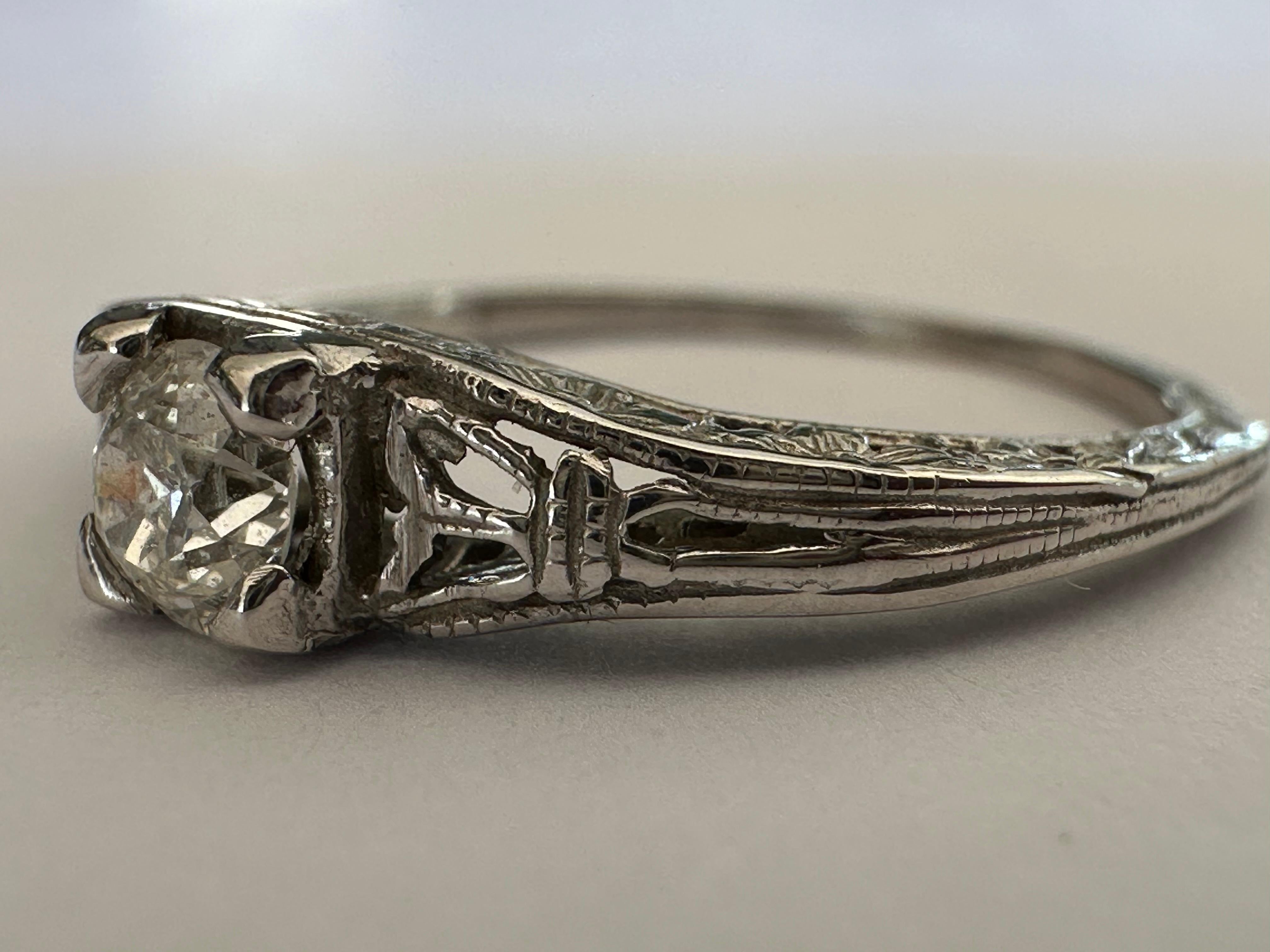 Cet étonnant bracelet Art déco en or blanc 14 carats présente une tige entièrement gravée de minuscules fleurs d'oranger et un perçage complexe pour créer une charmante monture pour le brillant diamant taille ancienne européenne de 0,28 carat,