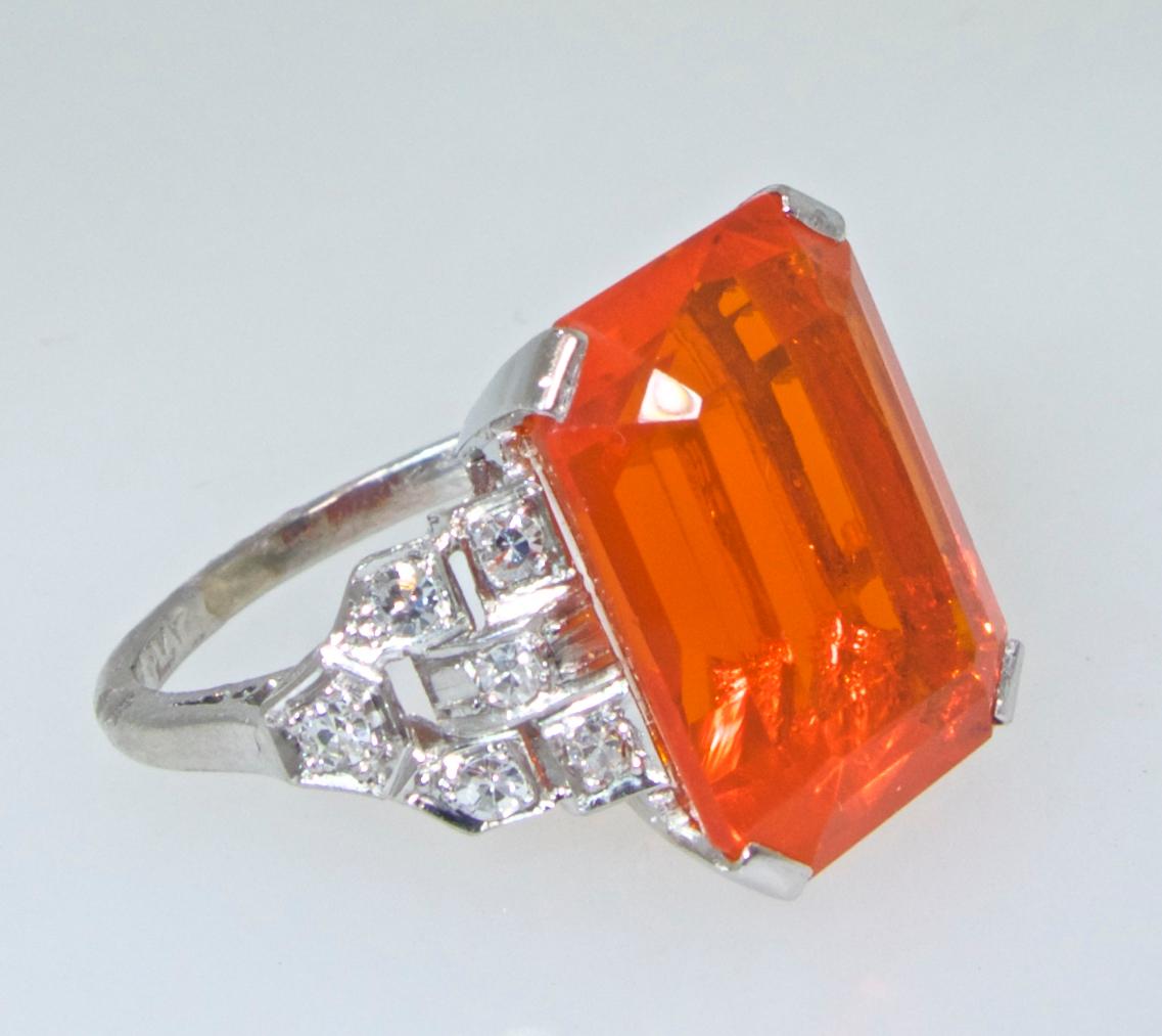 Art Deco diamond and platinum mounting centering a rectangular emerald cut very fine vivid natural fire opal measuring 15.1 by 11.1 by 7.5 mm. and estimated to weigh 6.5 cts.  The white round brilliant cut diamonds are bead set in this hand made