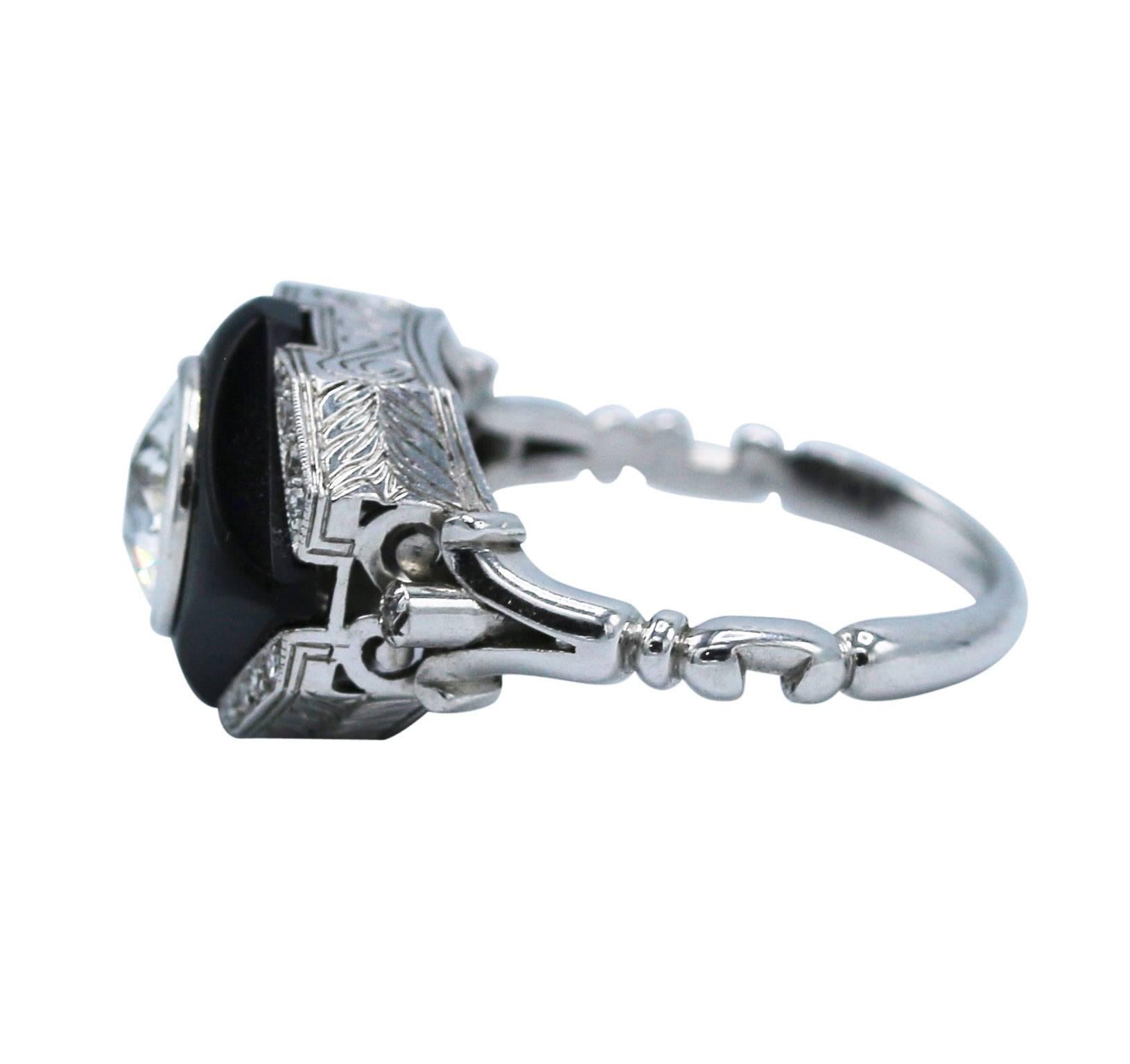 Art Deco white gold, diamond and onyx ring, France, set in the center with an old European-cut diamond weighing 1.38 carats, within a carved onyx frame, accented by single-cut diamonds weighing approximately 0.15 carat, gross weight 5.7 grams, size