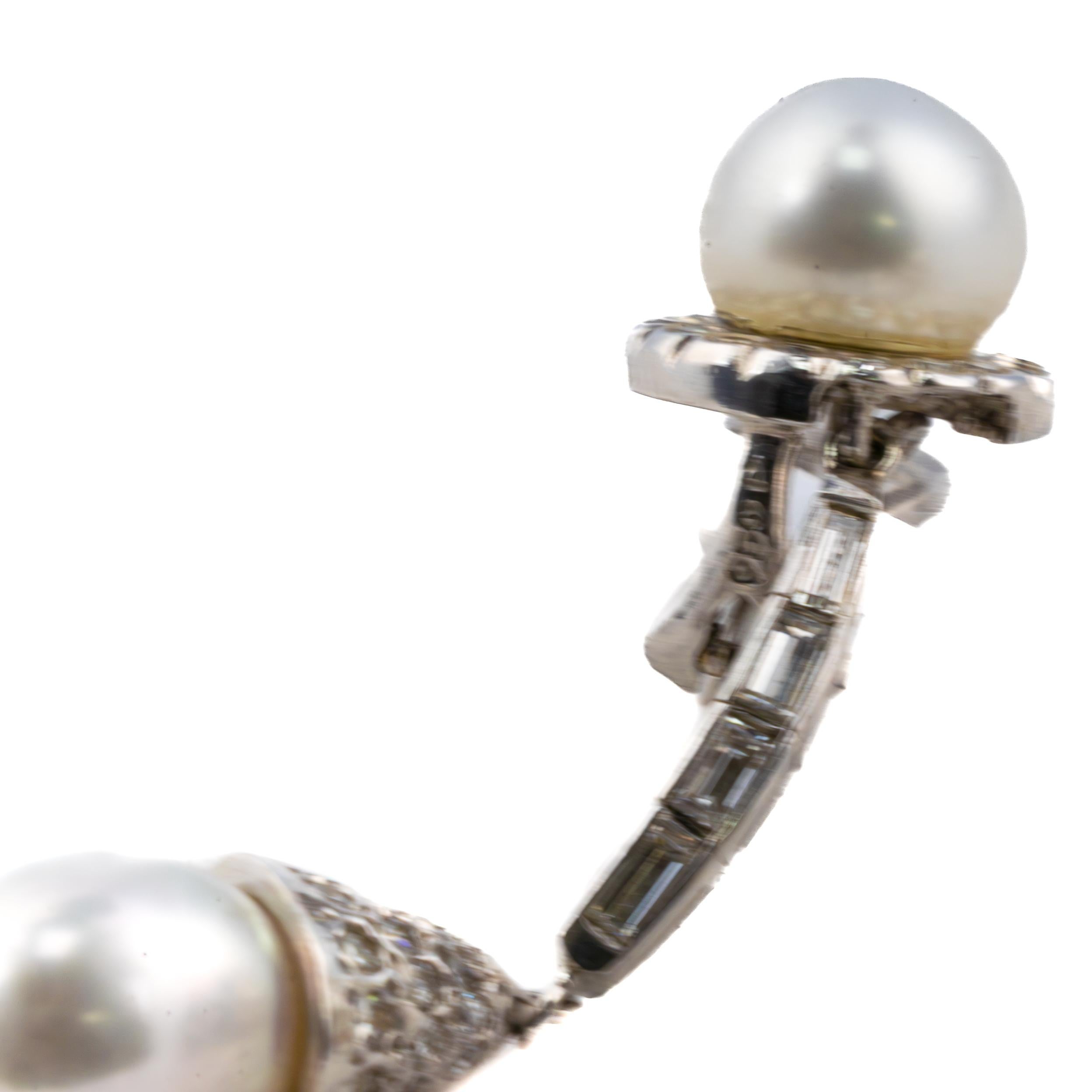 Art Deco Diamond and Pearl Drop Earrings in Platinum

Description:
A graceful pair of vintage drop earrings featuring luminous white pearls suspended from a refined line of baguette and round diamonds. Each earring is anchored by a pearl button top