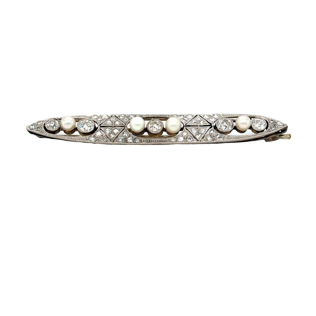 Exquisitely handcrafted in platinum this elongated oval Art Deco brooch features an openwork design centering three ovals of alternating bezel set European cut diamonds and lustrous 4.5-4.8 mm pearls. The brooch is further accentuated by 46 bead set