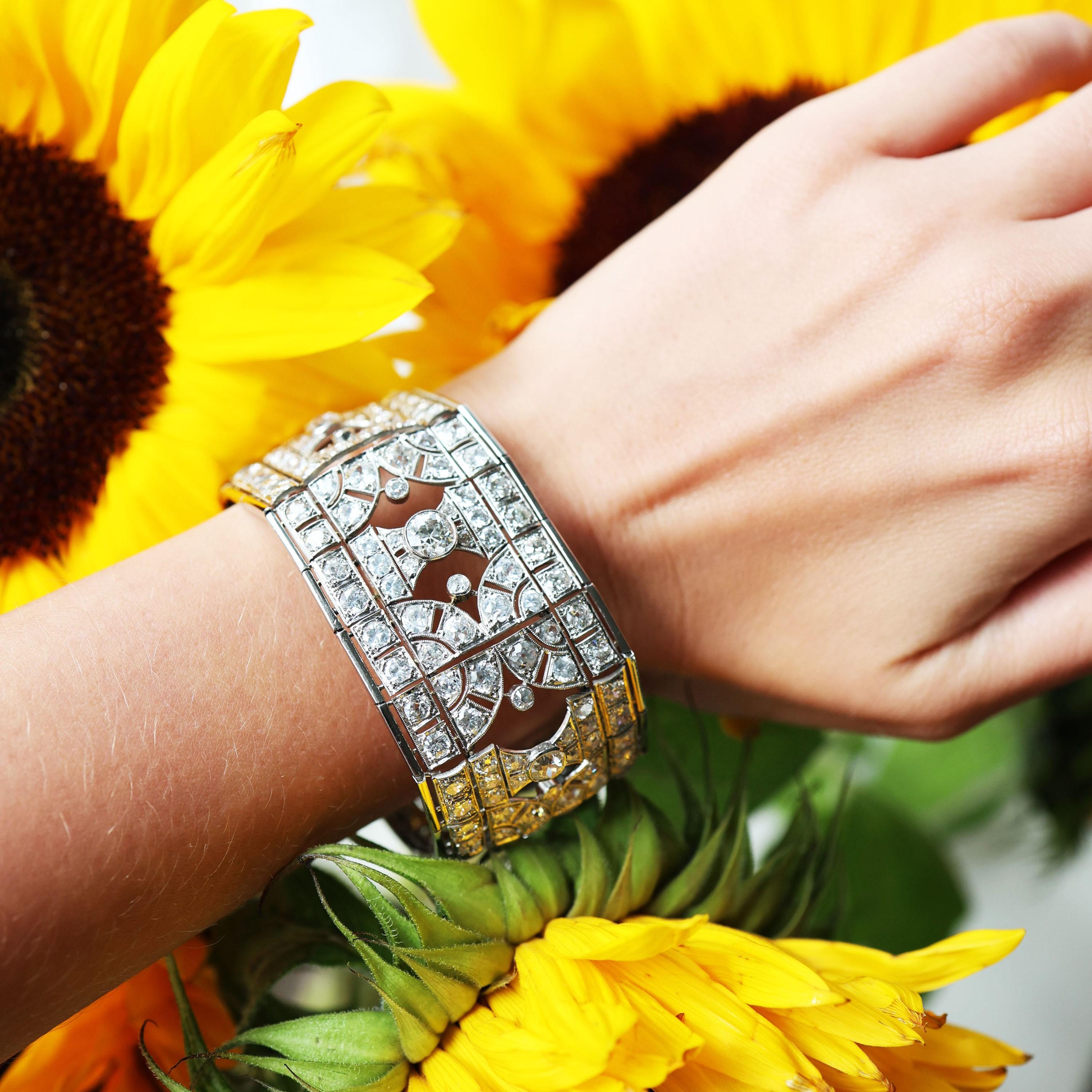 Ein Art-Deco-Armband aus Diamanten und Platin, mit einem zentralen Armband aus abwechselnden Paaren von gegenüberliegenden Halbkreisen und Sanduhrformen, mit größeren Diamanten im Altschliff, die von der Mitte aus verlaufen, in Reibefassungen, in