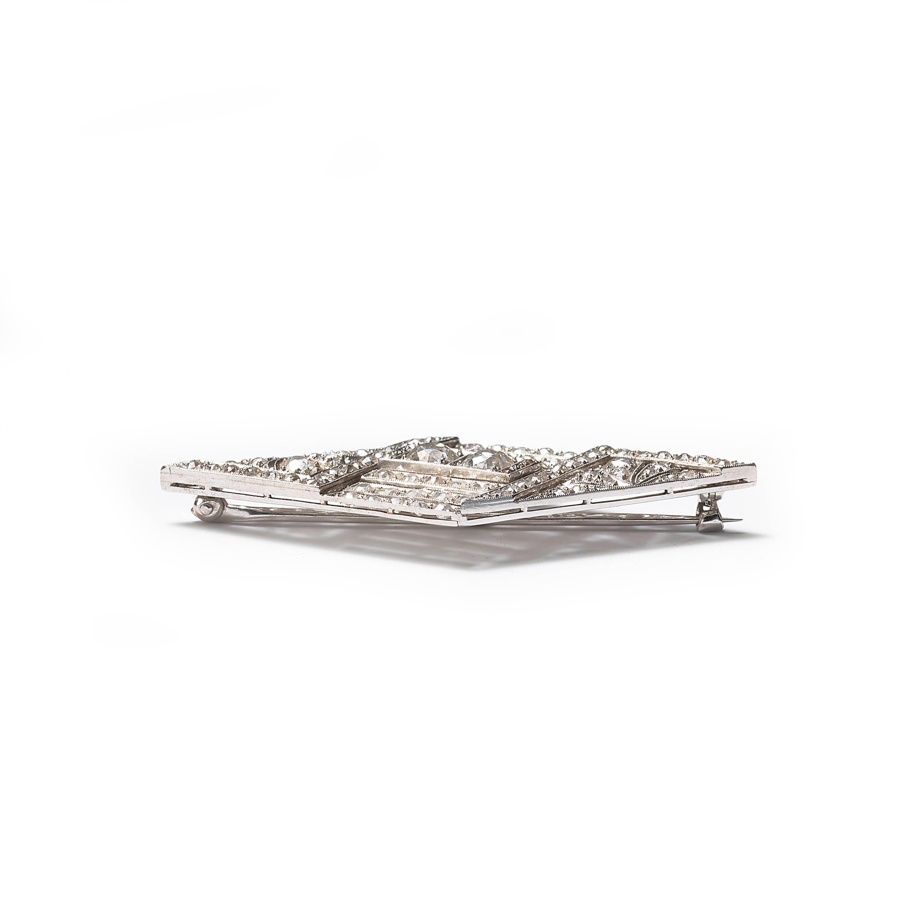 An Art Deco plaque brooch, with a rhombus-shaped outline and a geometric and foliate openwork design, set with old brilliant-cut diamonds, weighing an estimated total of 4.50 carats, with millegrain edges, mounted in platinum, with a pin and 'C'