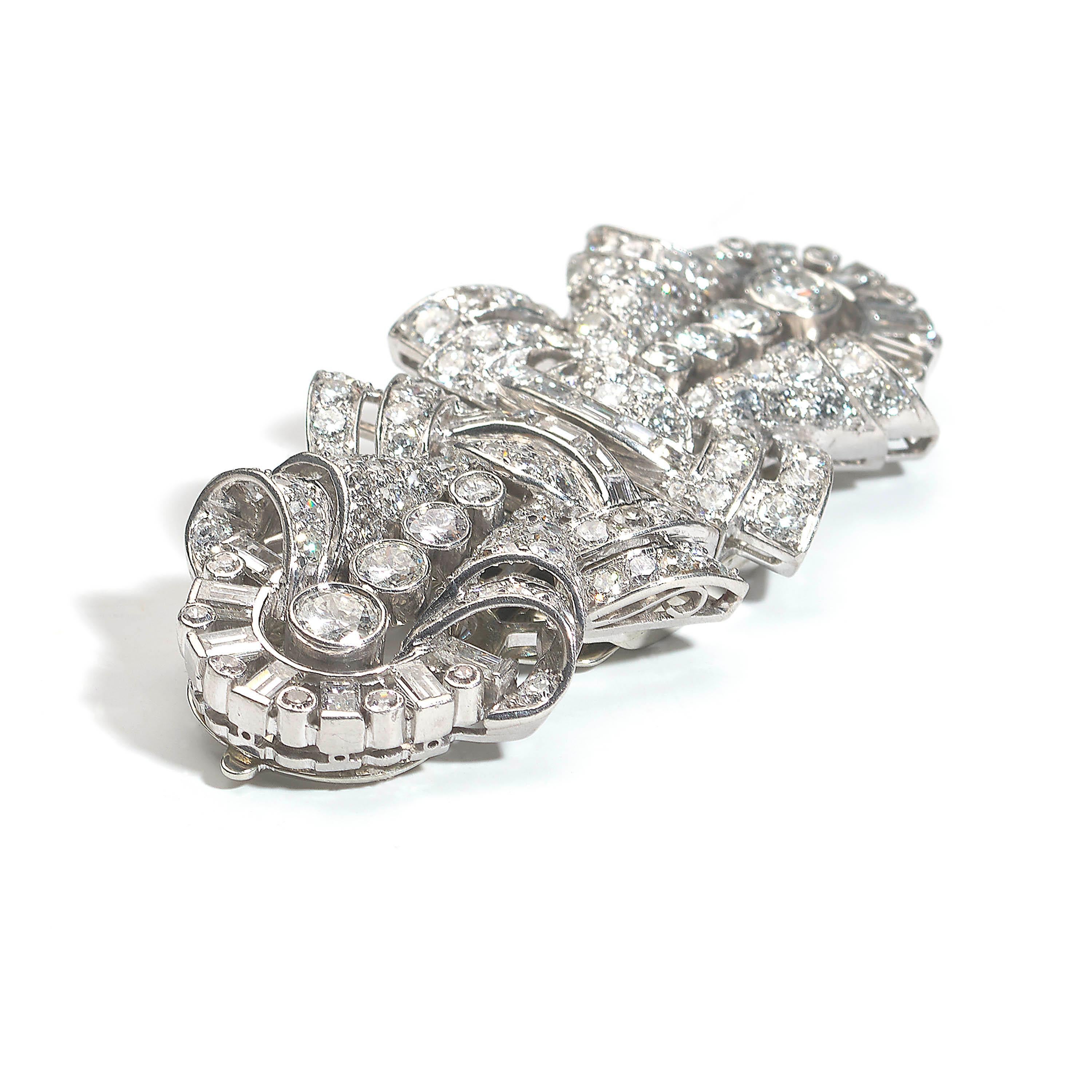 An Art Deco diamond and platinum double clip brooch, with a geometric, abstract bow design, with sunburst ends, set with round brilliant-cut, baguette and eight-cut diamonds, with a total weight of approximately 7.00ct, mounted in platinum, with