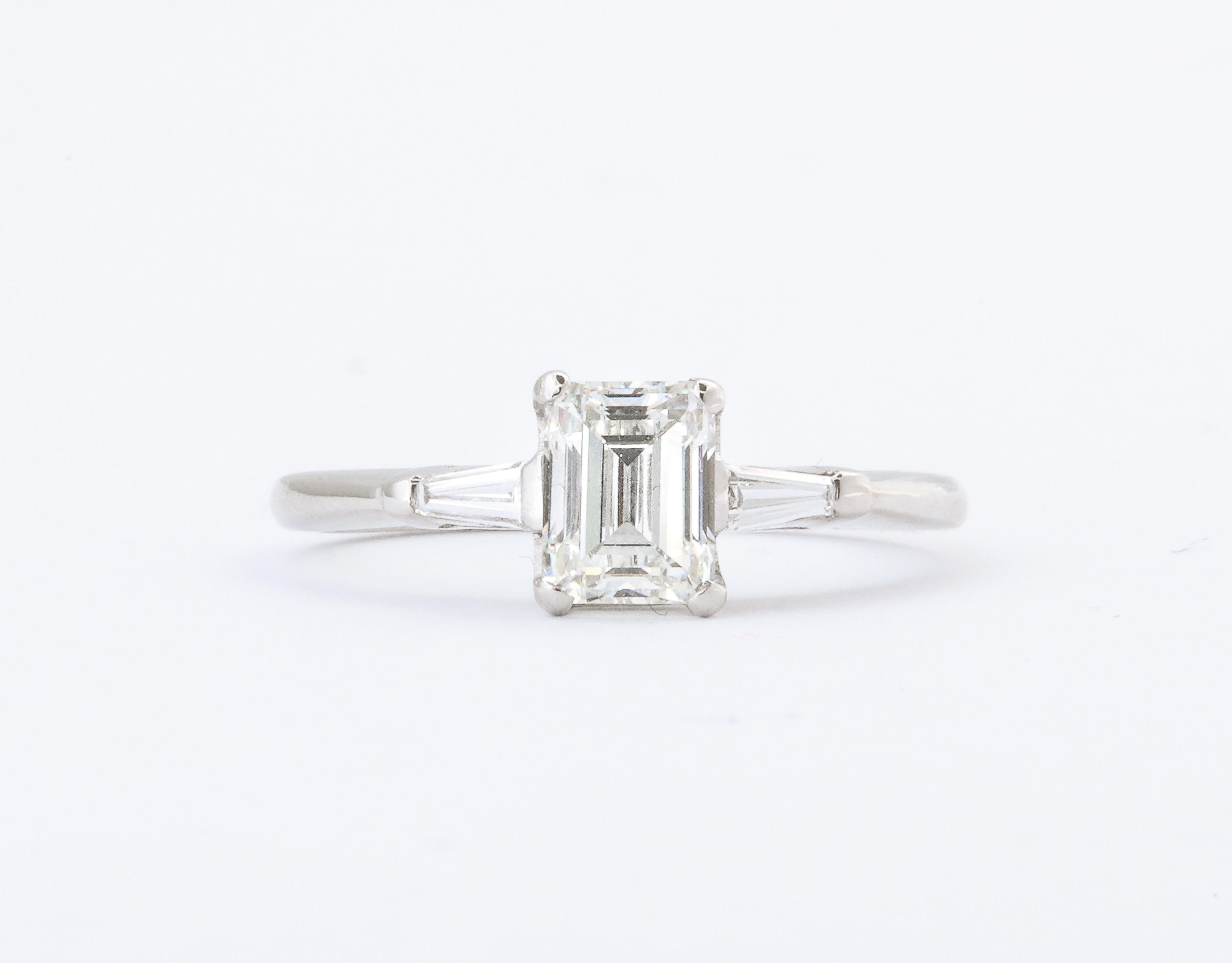 A classic Art Deco Diamond Emerald Cut Engagement Ring 1.07 Ct set in Platinum with a pair of tapered baguette diamonds flanking the center stone. Certificate from EGL Gemological Laboratory : VS1 H, 1.07 Ct
