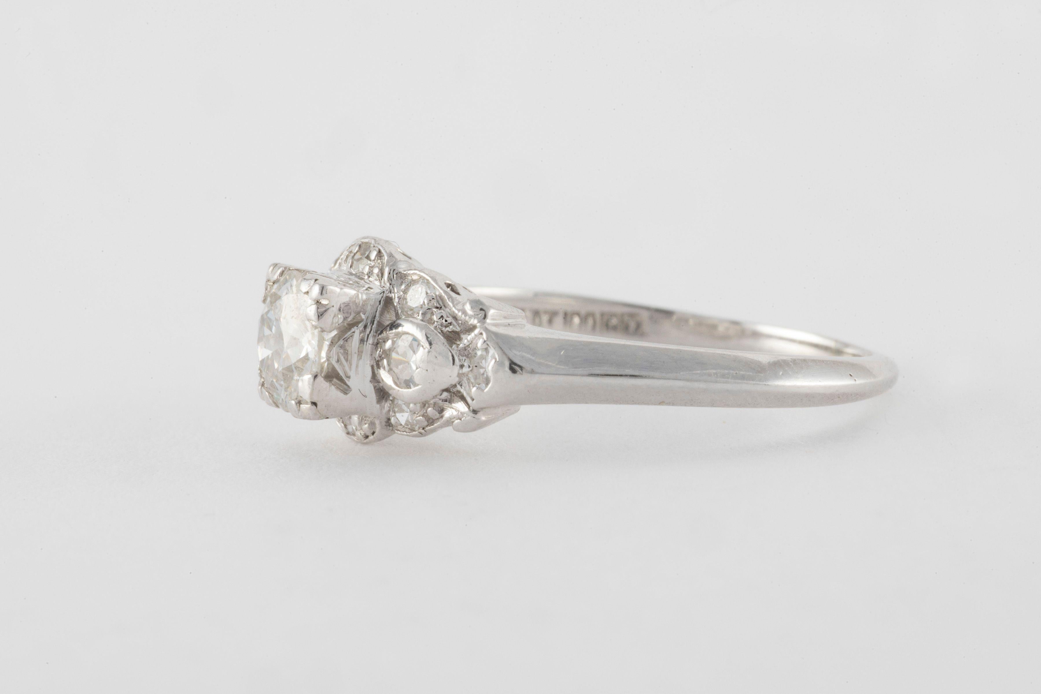 This glistening platinum band is designed around an Old European cut diamond center stone measuring approximately 0.67 carats, F color, SI1 clarity, 5.7 x 3mm and framed by ten single cut diamonds totaling approximately 0.25 carats. 
