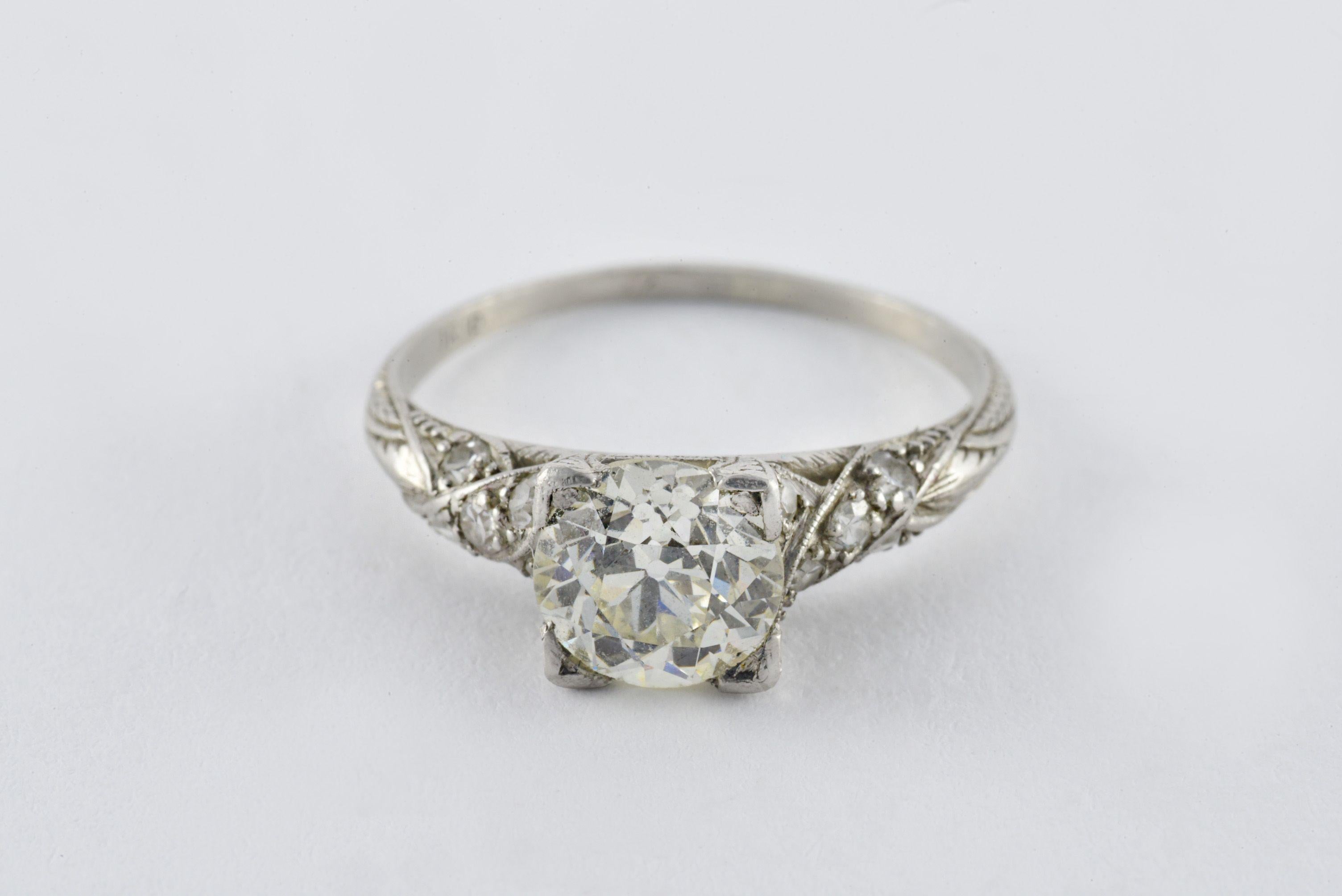 Crafted in the 1920s from platinum, this Art Deco ring is set with an Old European cut diamond measuring approximately 1.35 carats, L color, VS clarity and accented with ten single cut diamonds totaling 0.10 carats.  
