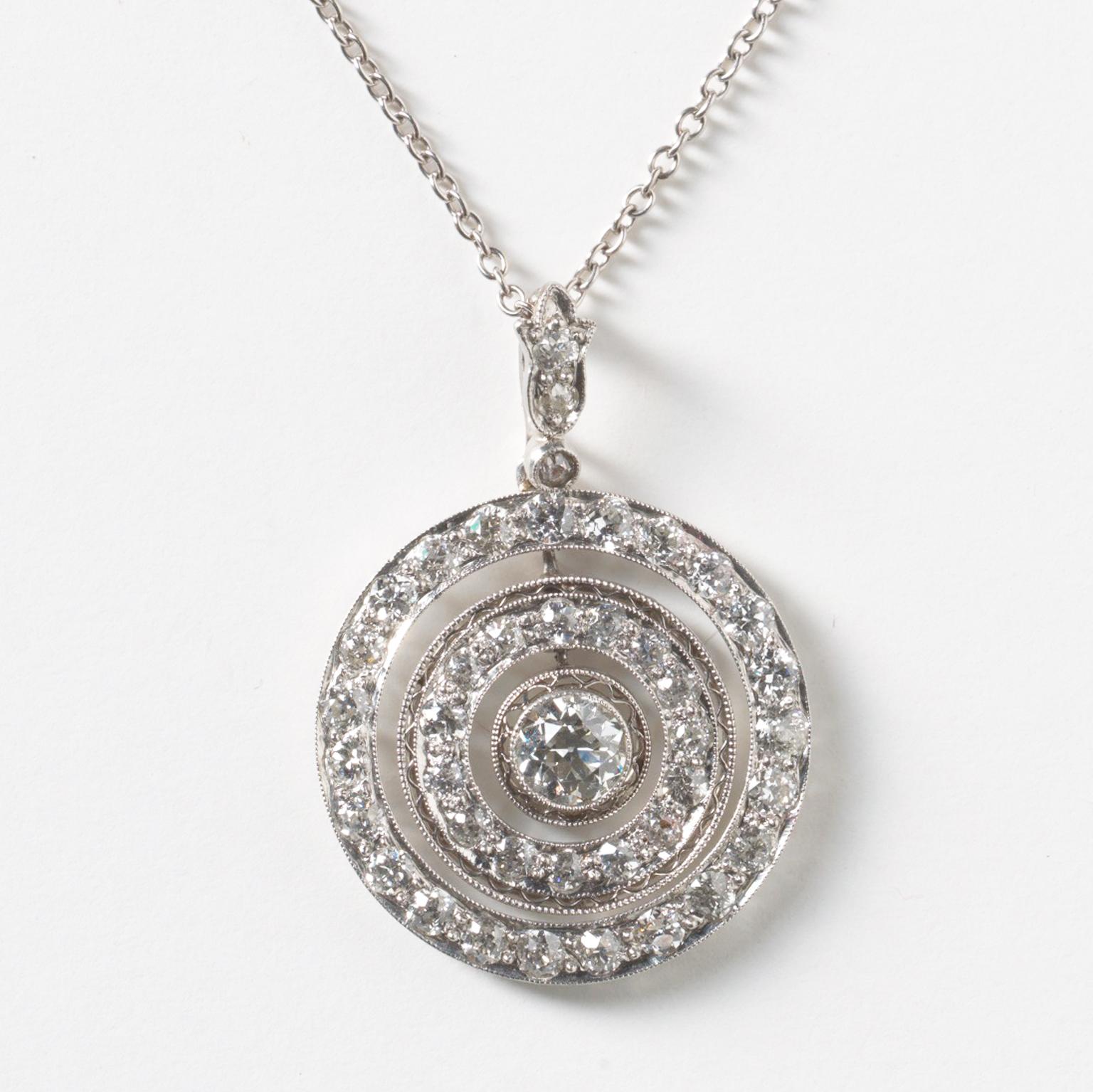A platinum and diamond target pendant with two concentric circles around an old cut centre stone (app. 0.4 ct.), the first circle is set with 15 old cut diamonds and the outer circle set with 24 brilliant cut diamonds with a leaf shaped bail (in