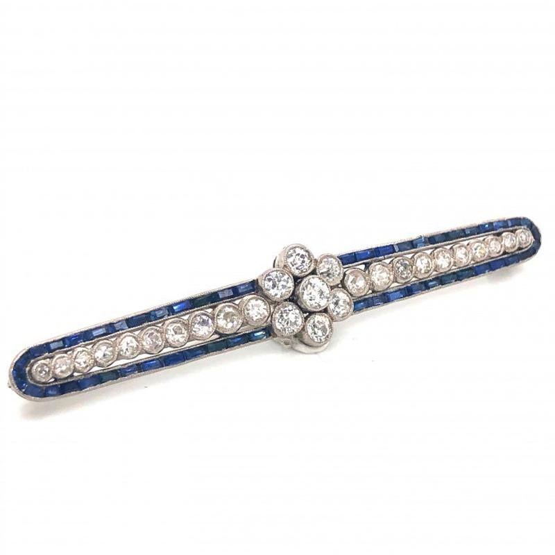 An Art Deco diamond and sapphire bar brooch, with a central, old-cut diamond daisy cluster, with ten graduating eight-cut diamonds, set each side, surrounded by channel set baguette-cut sapphires, with millegrain edges, mounted in platinum, stamped