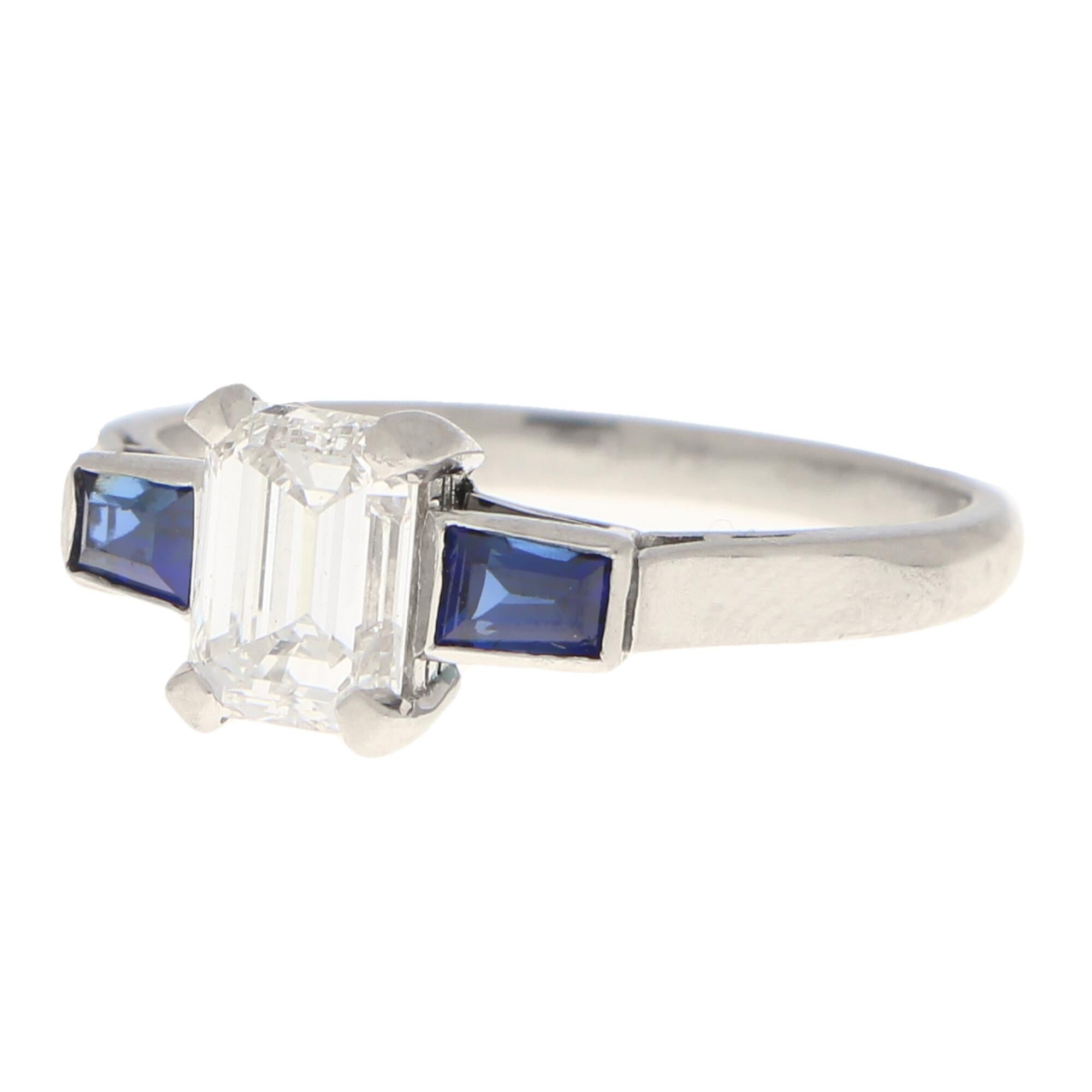 A rather unique GIA certified Art Deco emerald cut diamond and sapphire three stone ring set in platinum.

This alternative three stone is predominantly set with a lovely certified 0.91 carat emerald cut diamond which is securely four claw set to