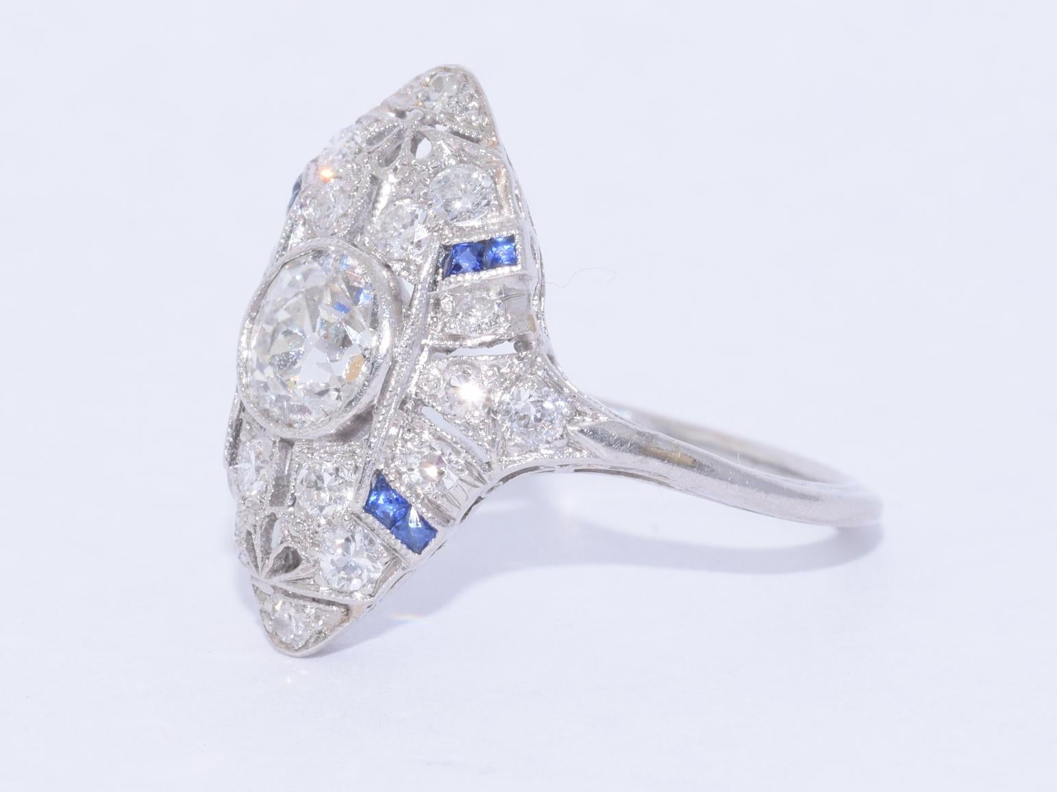 An old European diamond weighing approximately 0.65 carat, of approximately J/SI quality, is accented with single cut diamonds totaling approximately 0.35 carat and calibré sapphires mounted in platinum.