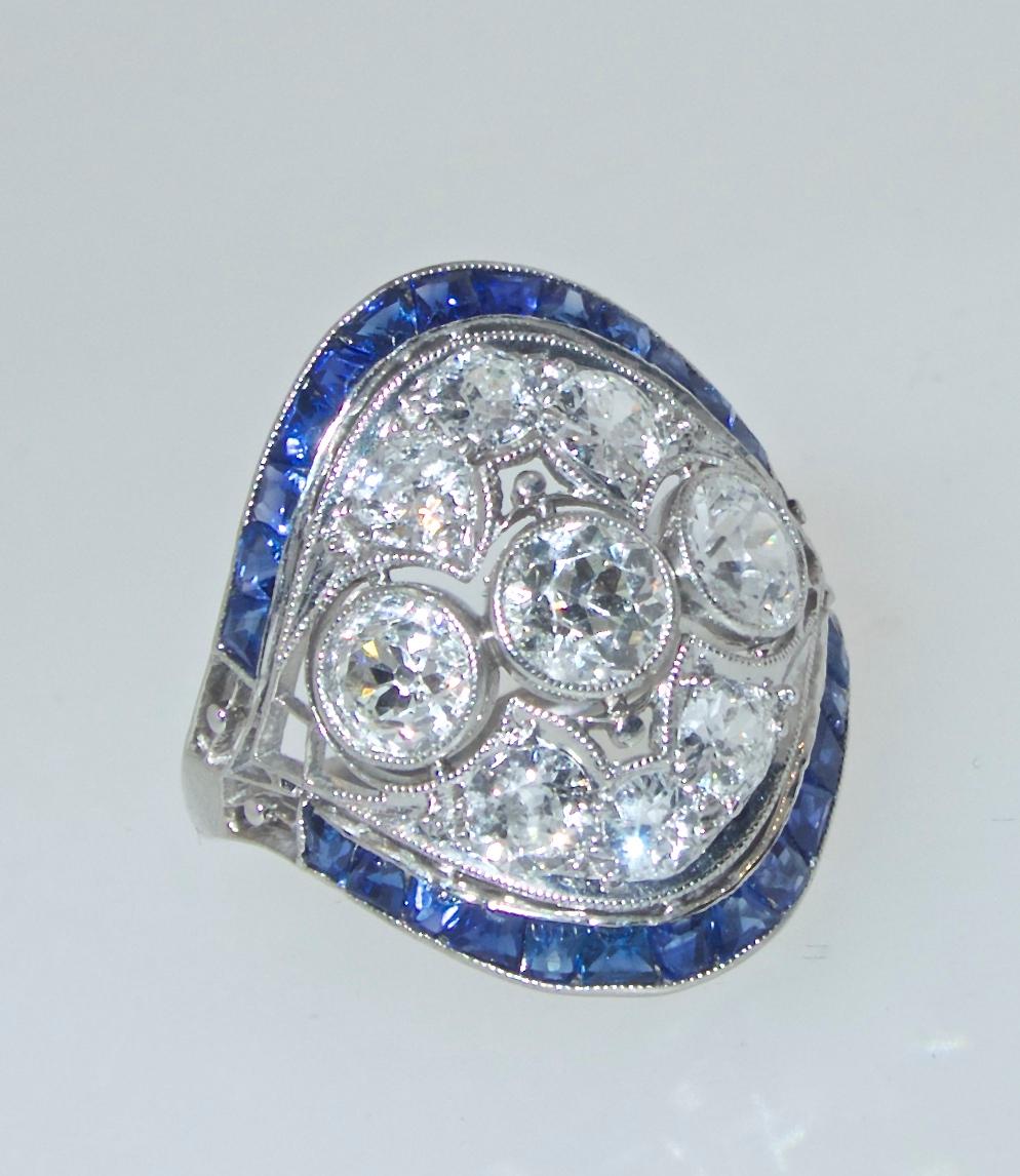 Platinum, diamond and sapphire ring, the 26 calibre cut natural bright blue sapphires surround the center European cut diamonds. The 9 diamonds weigh approximately 1.45 cts.  The diamonds are all European cut, near colorless (H) and very slightly