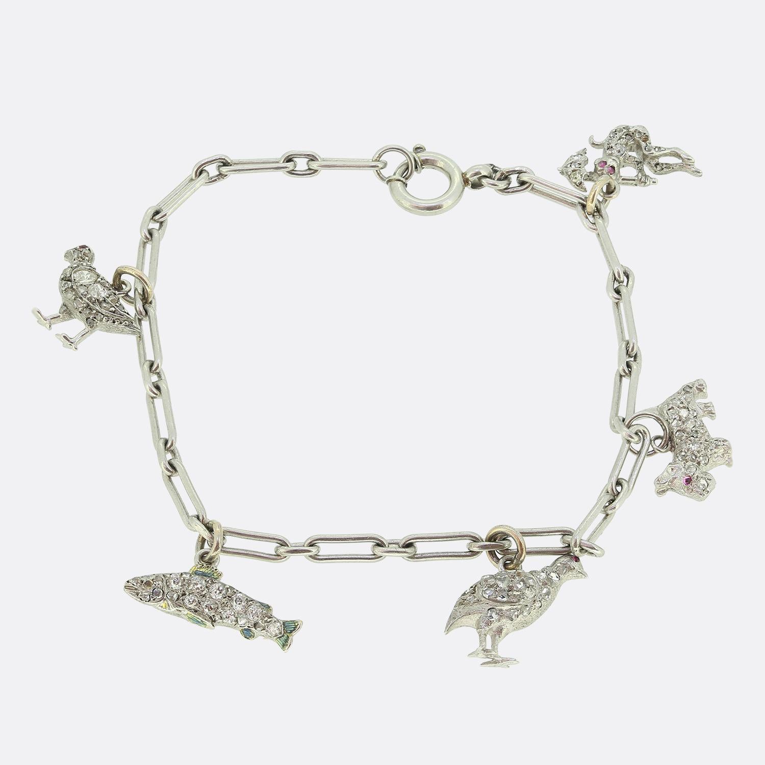 Here we have a platinum chain link bracelet featuring an array of delightful animal charms including a duo of birds, a fish, scottie dog and a monkey. Each charm is adorned with round faceted old mine and rose cut diamonds, adding a touch of sparkle