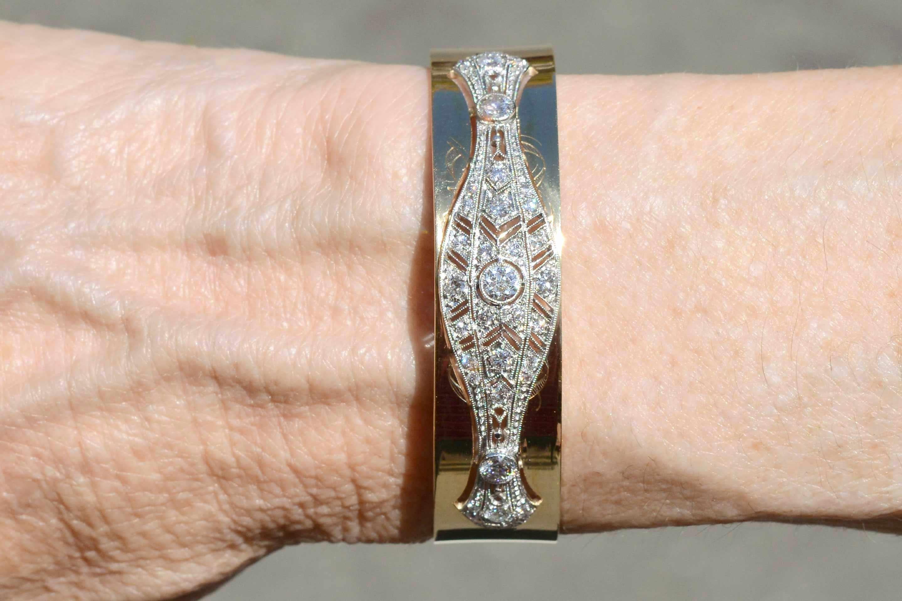 The Rochester Art Deco diamond bangle bracelet is a wide cuff featuring exquisite antique filigree work. The 2 tone 14kt yellow gold frames a a platinum brooch with nearly 1 carat of sparkling old European diamonds arranged in a geometric chevron