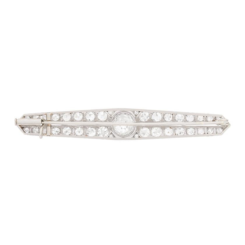 This diamond brooch features a centre diamond weighing 1.35 carat. It is claw set and estimated to be F in colour and VS in clarity. The two rows of diamonds which are grain set either side of the centre diamond are made up of old cuts. The