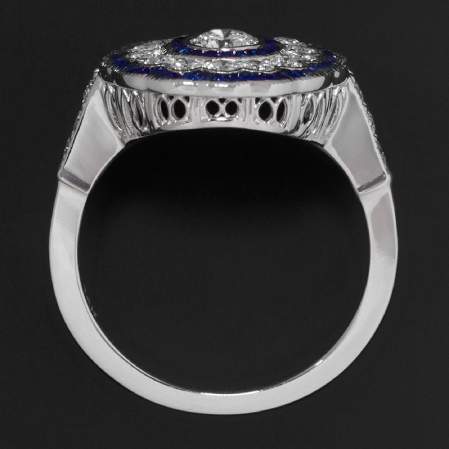 Art Deco Style ring features a very high quality round brilliant cut diamond surrounded by a glamorous triple halo of vibrant diamonds and royal blue natural sapphires. The ¼ carat F VS2 diamond is phenomenal in quality, bright white, and