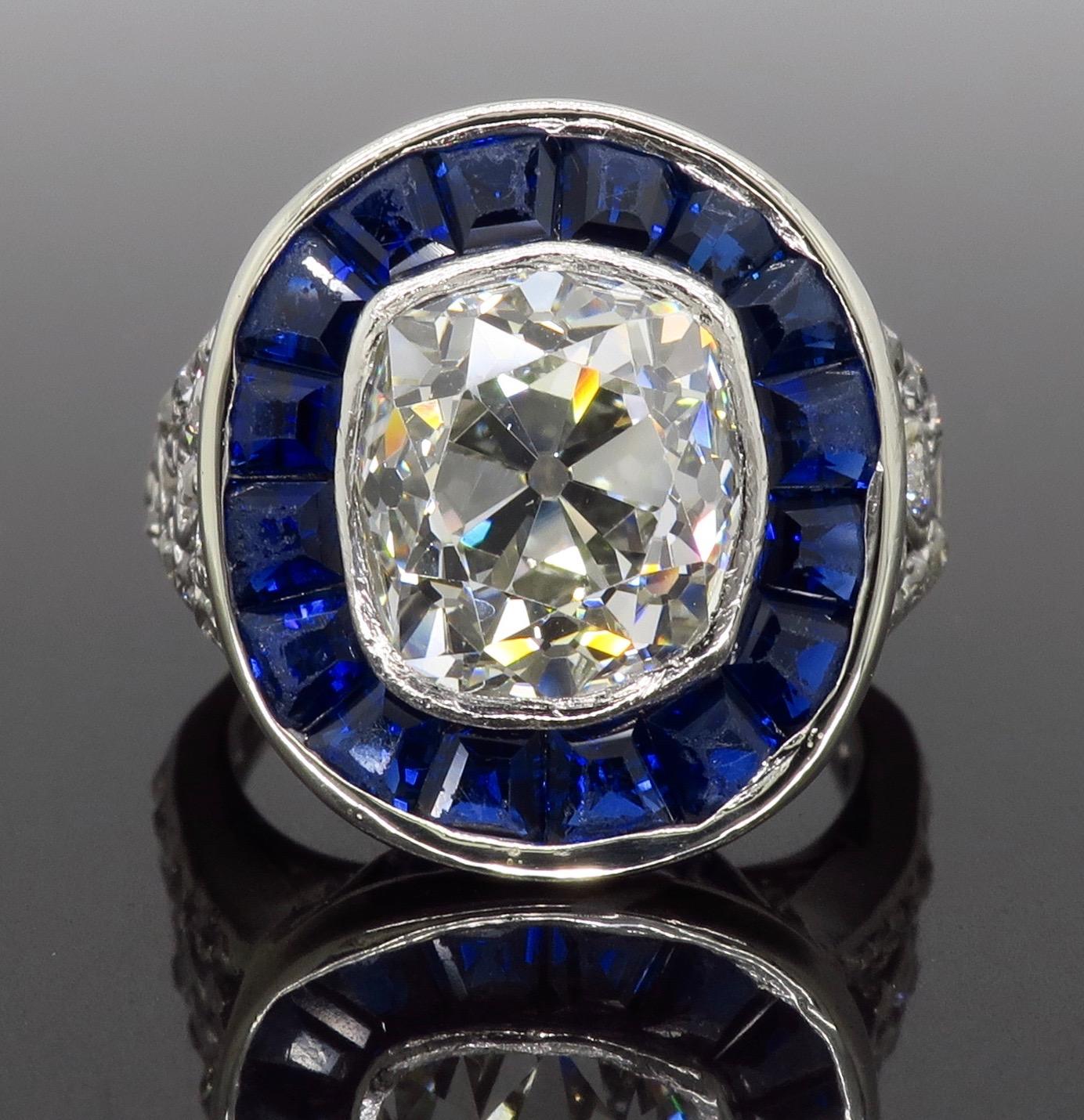Vintage art deco ring featuring an approximately 3.25ct Old Miners Cut Diamond surrounded by irregular cut Blue Sapphires handcrafted in platinum.

Gemstone: Diamond & Sapphire
Gemstone Carat Weight: 16 Irregular Cut Blue Sapphires
Center Diamond