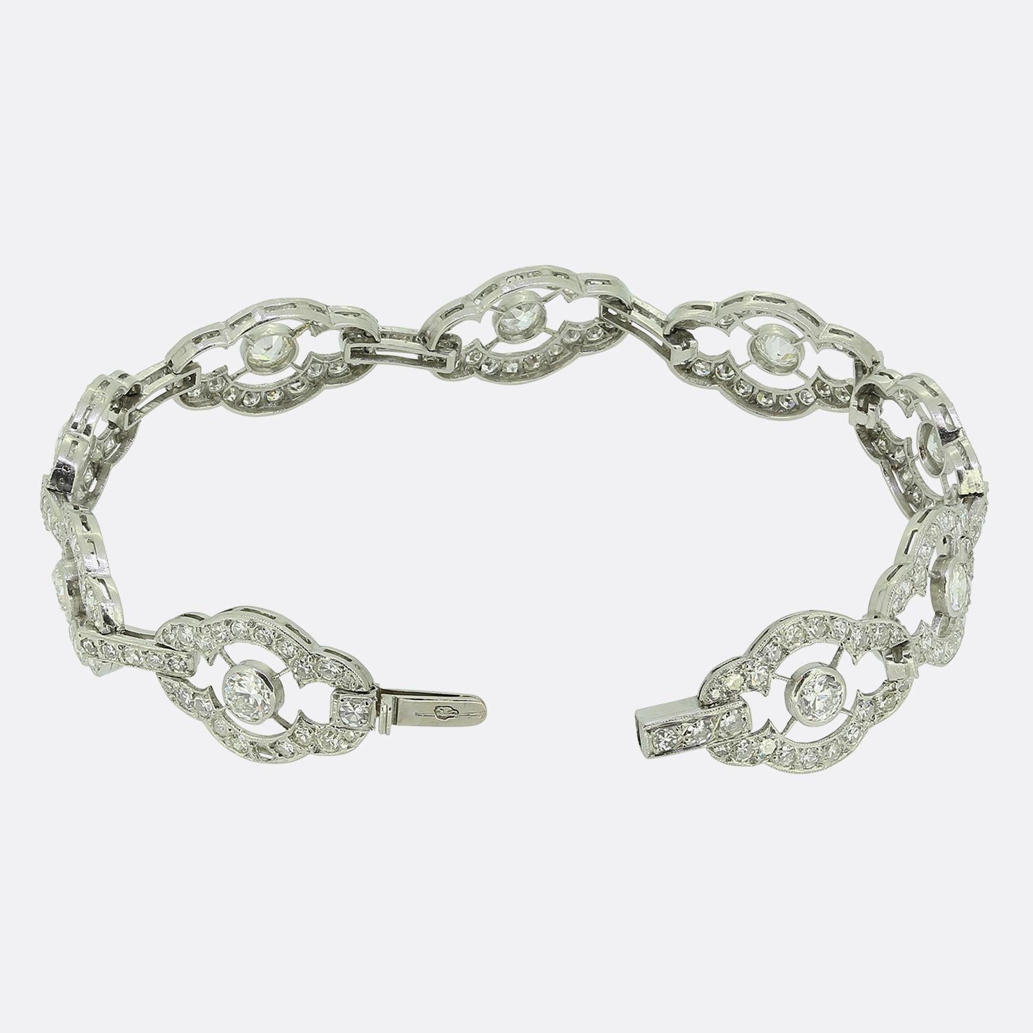 Aquí tenemos una maravillosa  con una serie de intrincados motivos curvilíneos, cada uno de ellos adornado con un diamante redondo de talla antigua. El diseño presenta una armoniosa mezcla de diamantes calados y engastados en milgrain, creando un
