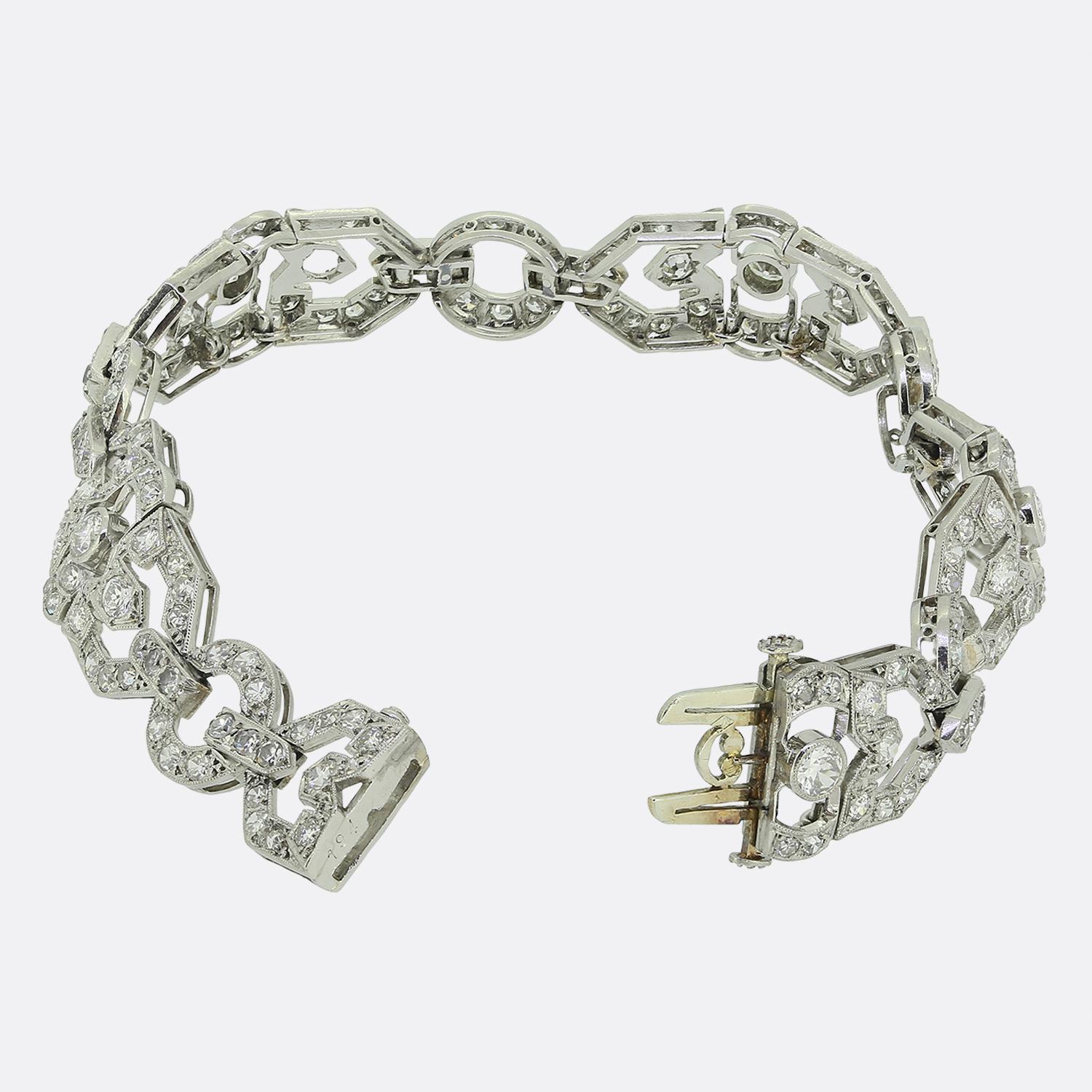 Aquí tenemos un exquisito brazalete Art Déco elaborado con precisión y elegancia. Esta pieza está fabricada en oro blanco de 18 ct, y luce una armoniosa mezcla de diamantes blancos talla vieja europea y talla única. Los diamantes están
