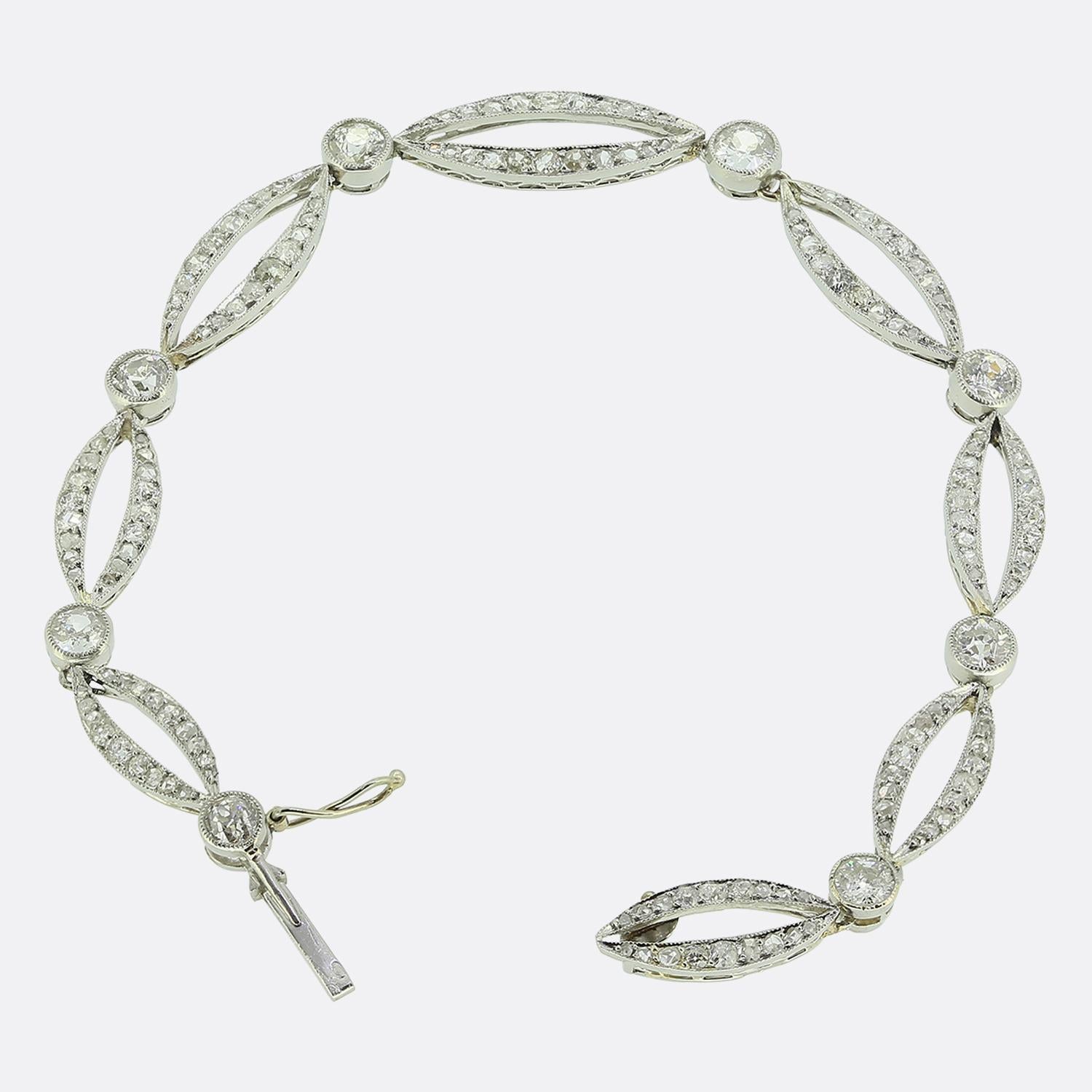 Si tratta di uno squisito bracciale Art Déco che presenta una serie di eleganti maglie di forma ovale, ognuna delle quali è impreziosita da scintillanti diamanti antichi e rosa. Tra queste maglie sono incastonati diamanti tondi sfaccettati taglio