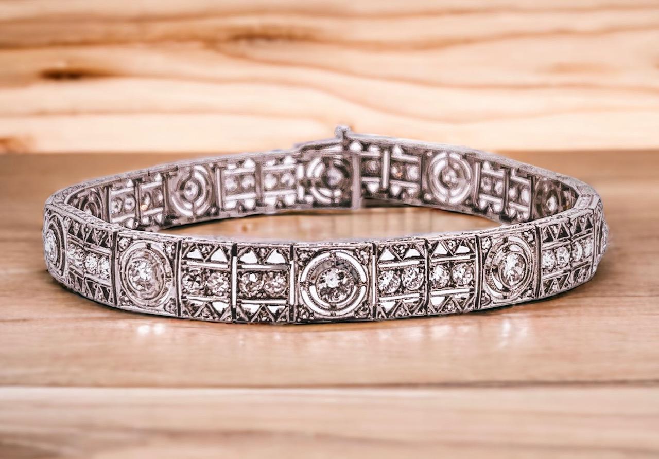 Art-Deco-Armband mit Diamanten aus Platin. Das fein durchbrochene Gliederarmband mit einer zentralen Reihe von Diamanten, die von 10 größeren Diamanten in Halo-Fassungen durchsetzt sind. Farbe G bis I. Reinheit si bis I1. 18,5 cm Länge. 
0,8 cm