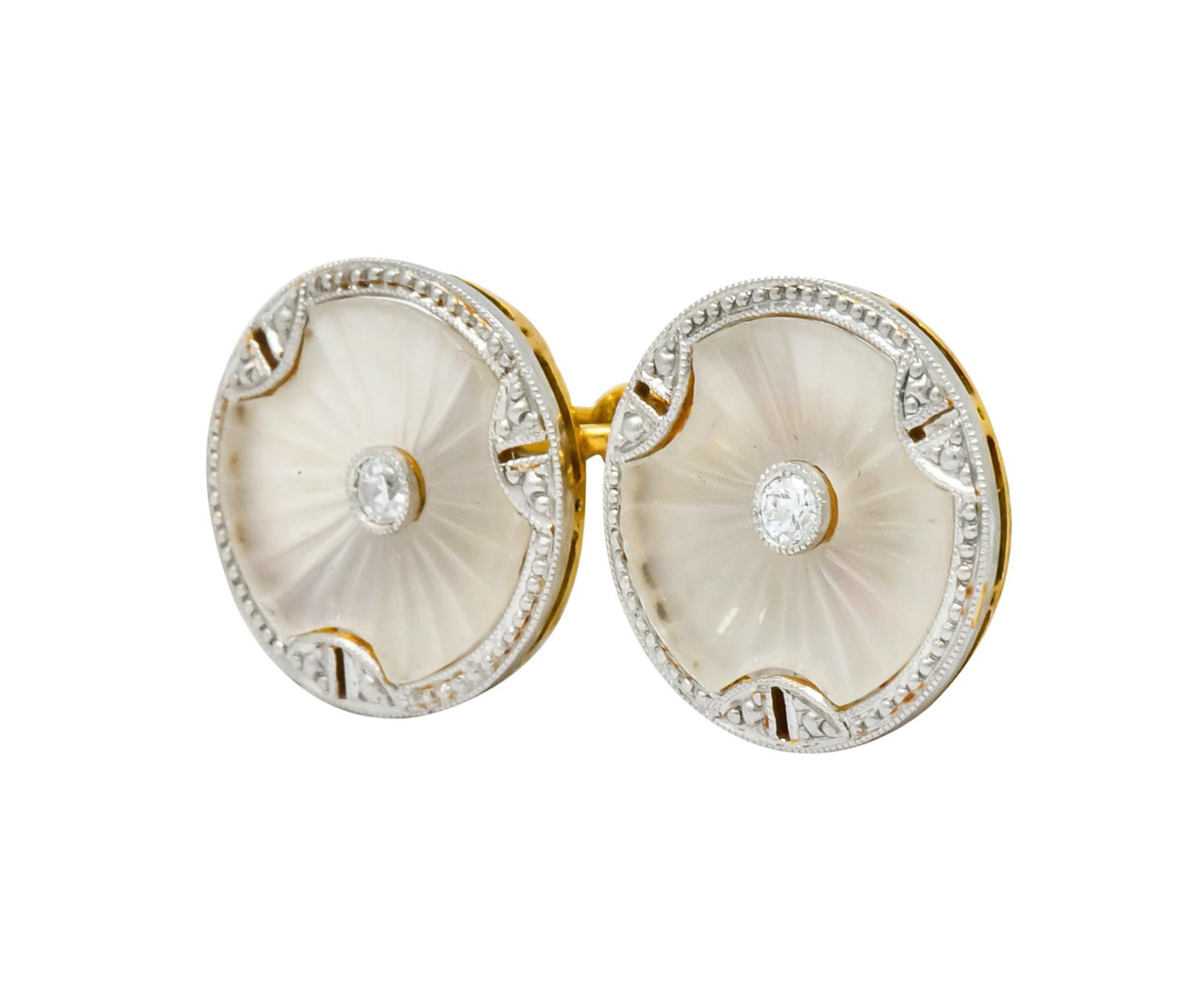 Link style cufflinks terminating as two round, platinum-topped, millegrain frames bezel set with camphor glass

Camphor glass is deeply engraved with a radiating burst motif and centers transitional cut diamonds weighing in total 0.12 carat,