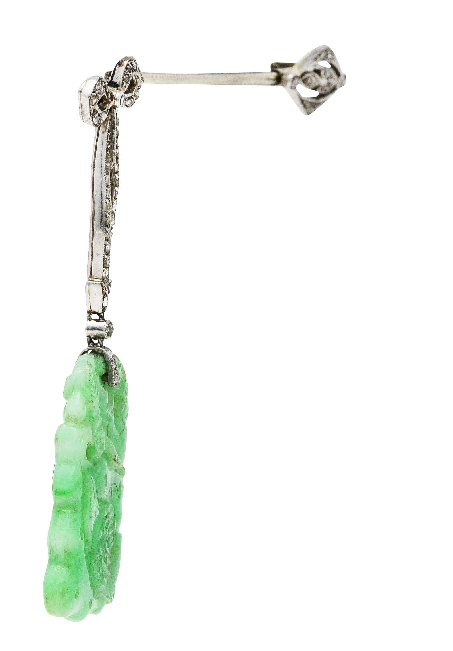 Brooch is designed as jabot style bar brooch

With articulated ribbon motif suspending carved jade drop

Translucent green to pastel green in color with subtle mottling

Accented throughout with rose cut diamonds - quality consistent with