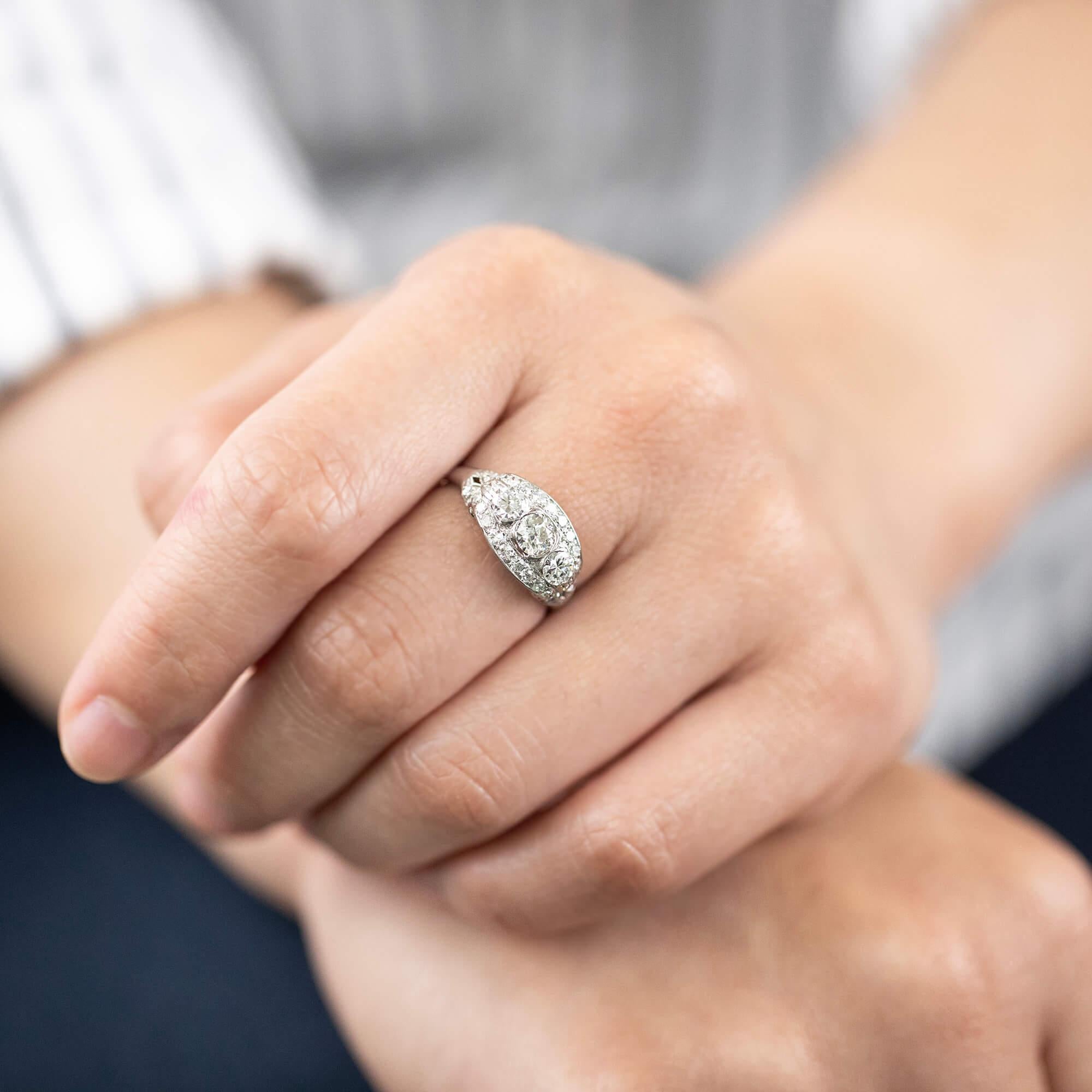 Art-Deco-Ring mit gewölbtem und körnig gefasstem Dreistein-Diamantring, besetzt mit Diamanten im Übergangs-Brillantschliff. 

Diamant: Ein 4,55 mm großer Übergangsbrillant, Farbe J-K, Material SI1, geschätztes Gewicht 0,34ct
Diamanten: Zwei 3,9 mm