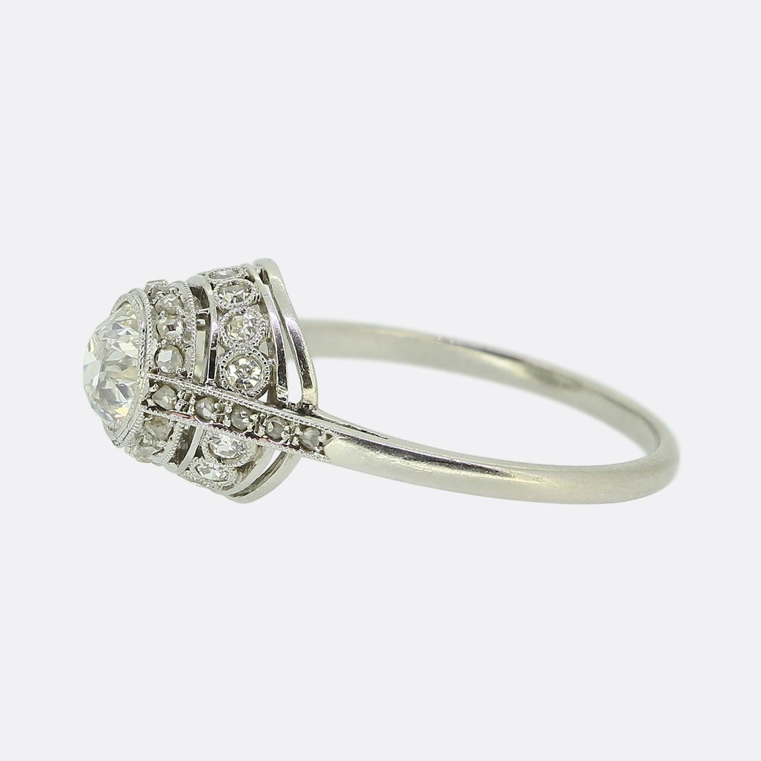 Ecco uno splendido anello con diamante realizzato all'epoca in cui lo stile Art Déco era all'apice del design. Un singolo diamante rotondo sfaccettato di taglio antico si trova particolarmente orgoglioso in cima a due file di diamanti finemente