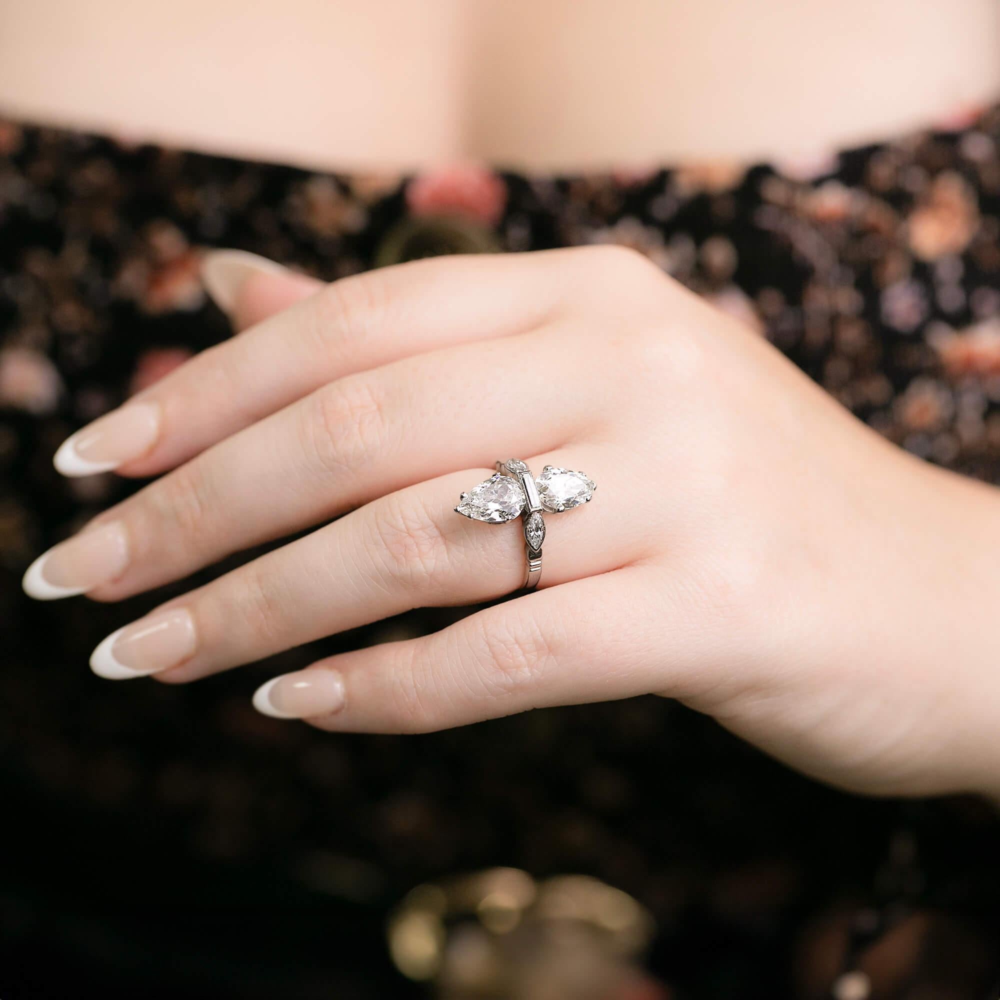 This is a spectacular Art Deco cocktail ring hand-crafted in platinum, features two antique pear cut diamonds facing north-south with a baguette and marquises cut diamond through the centre. This ring sits perfectly on the finger. Stamped with