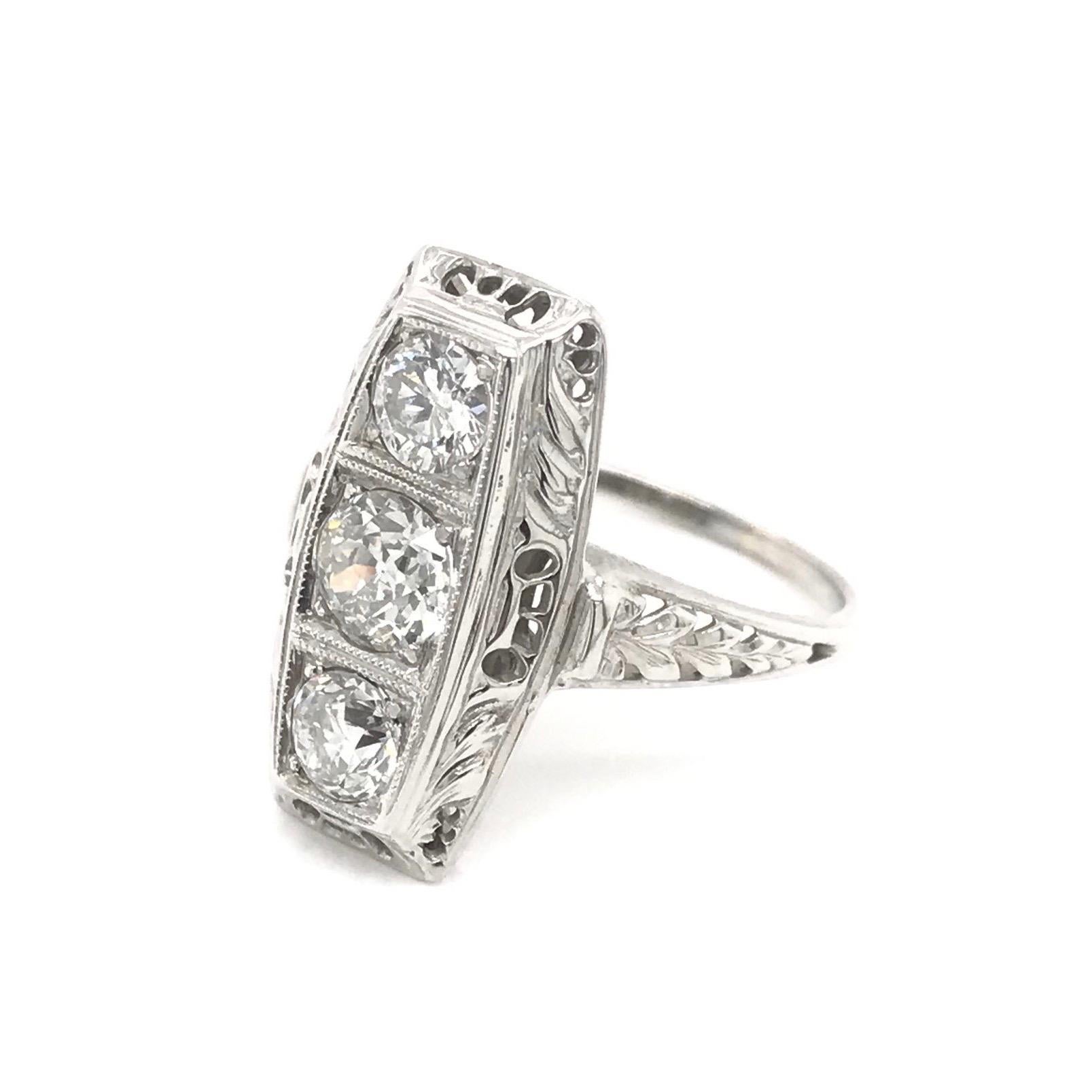 This piece was handcrafted sometime during the Art Deco design period ( 1920-1940 ). The setting is 18k white gold and features three Old European Cut diamonds set north to south. The diamonds are in the H to I color range and the combined total