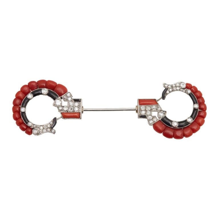 A chic Art Deco jabot pin embellished with coral, onyx, and diamond.