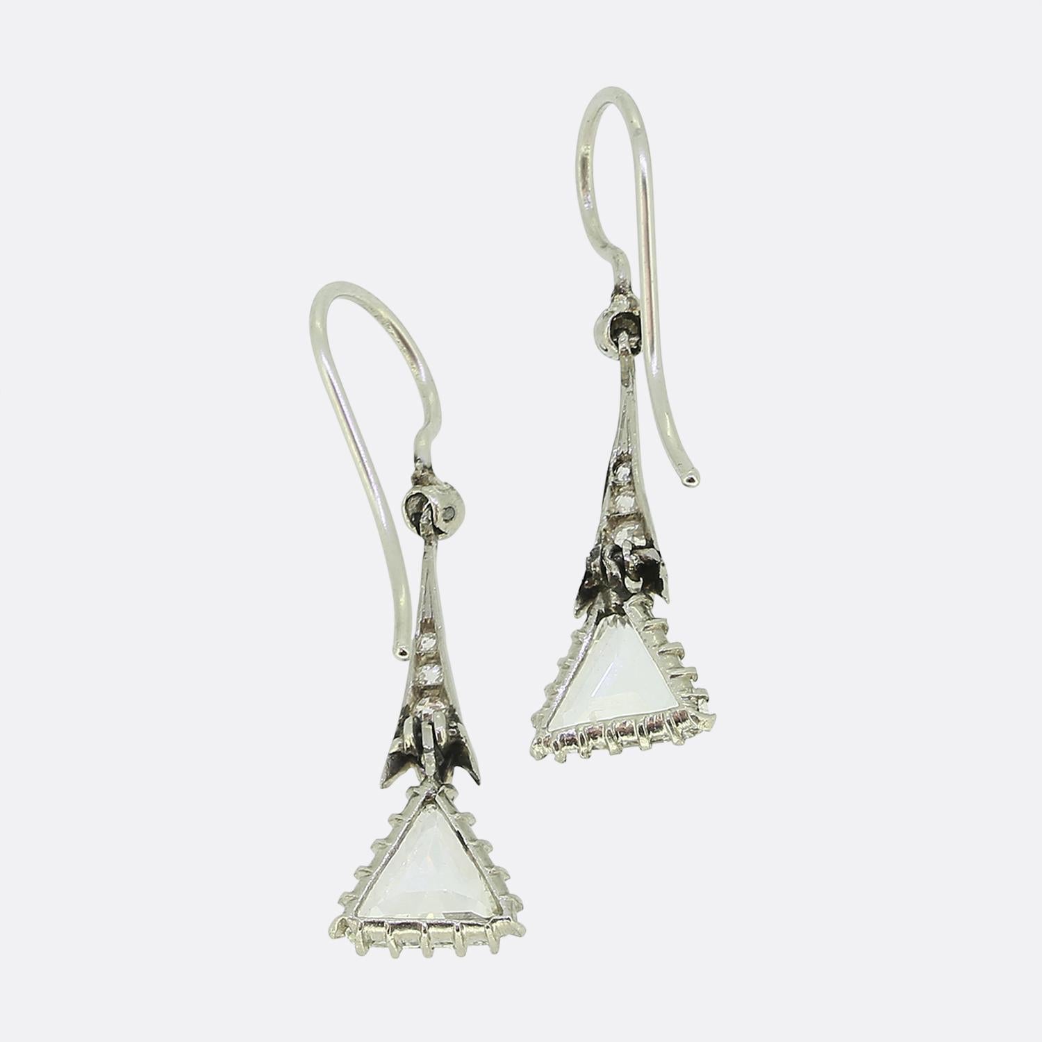 Ecco uno squisito paio di orecchini a goccia realizzati con precisione ed eleganza. Ogni orecchino mette in mostra uno splendido diamante bianco e pulito dal taglio a trilione, sospeso con grazia alla base di ogni pezzo. Queste pietre primarie sono